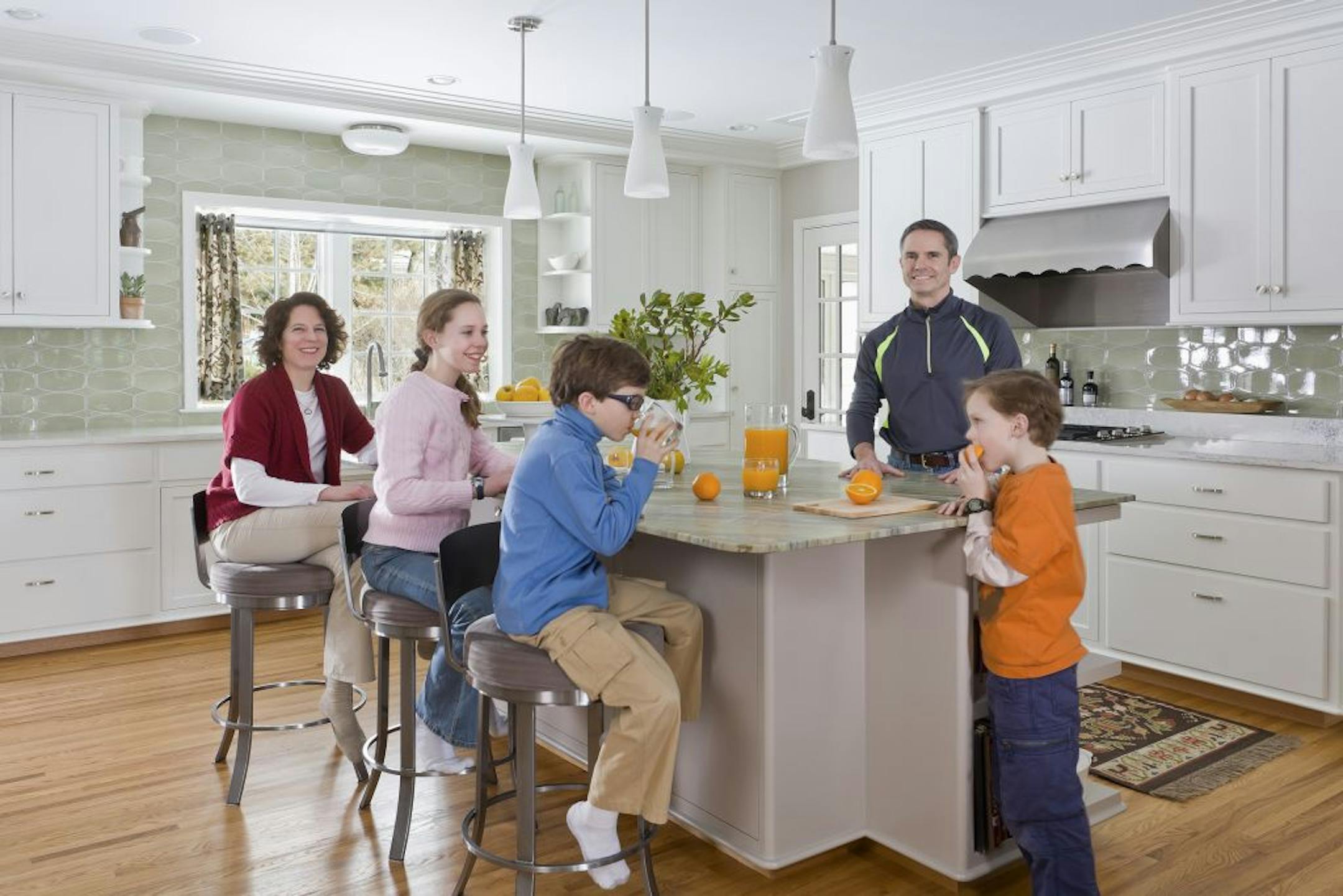 Elizabeth Burnett, left, Adam Mans, standing, and their three kids, left to right, Abby, Henry and Peter, love hanging out in their new family-friendly kitchen.