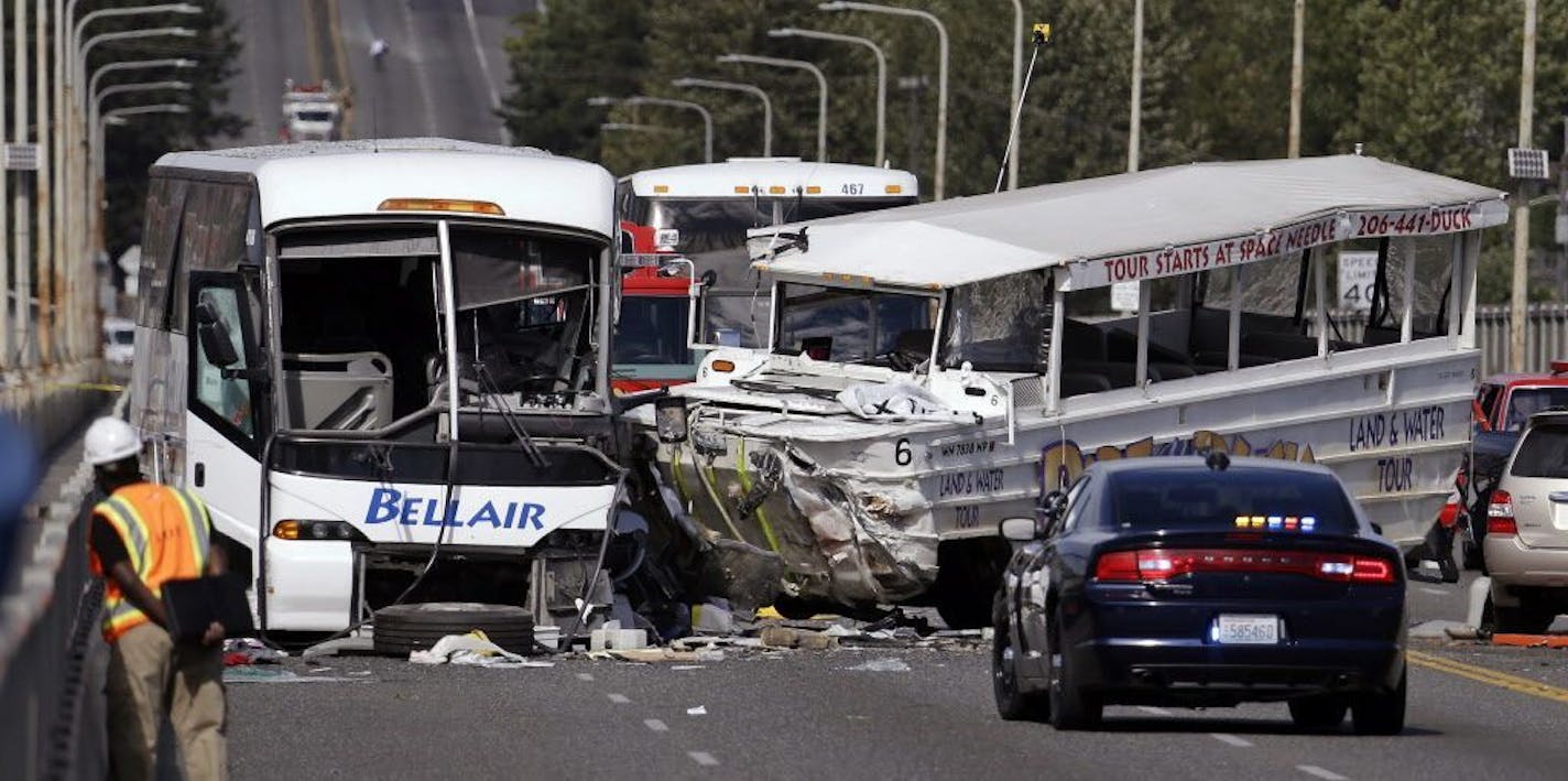 FILE - In this Sept. 24, 2015, file photo, a "Ride the Ducks" amphibious tour bus, right, and a charter bus remain at the scene of a multiple fatality collision on the Aurora Bridge in Seattle. With an ability to travel by both land and sea, duck boats have long been tourist attractions for sightseers around the U.S. A spate of deadly accidents has forced safety improvements and has prompted some to call for a total ban on the vehicles.