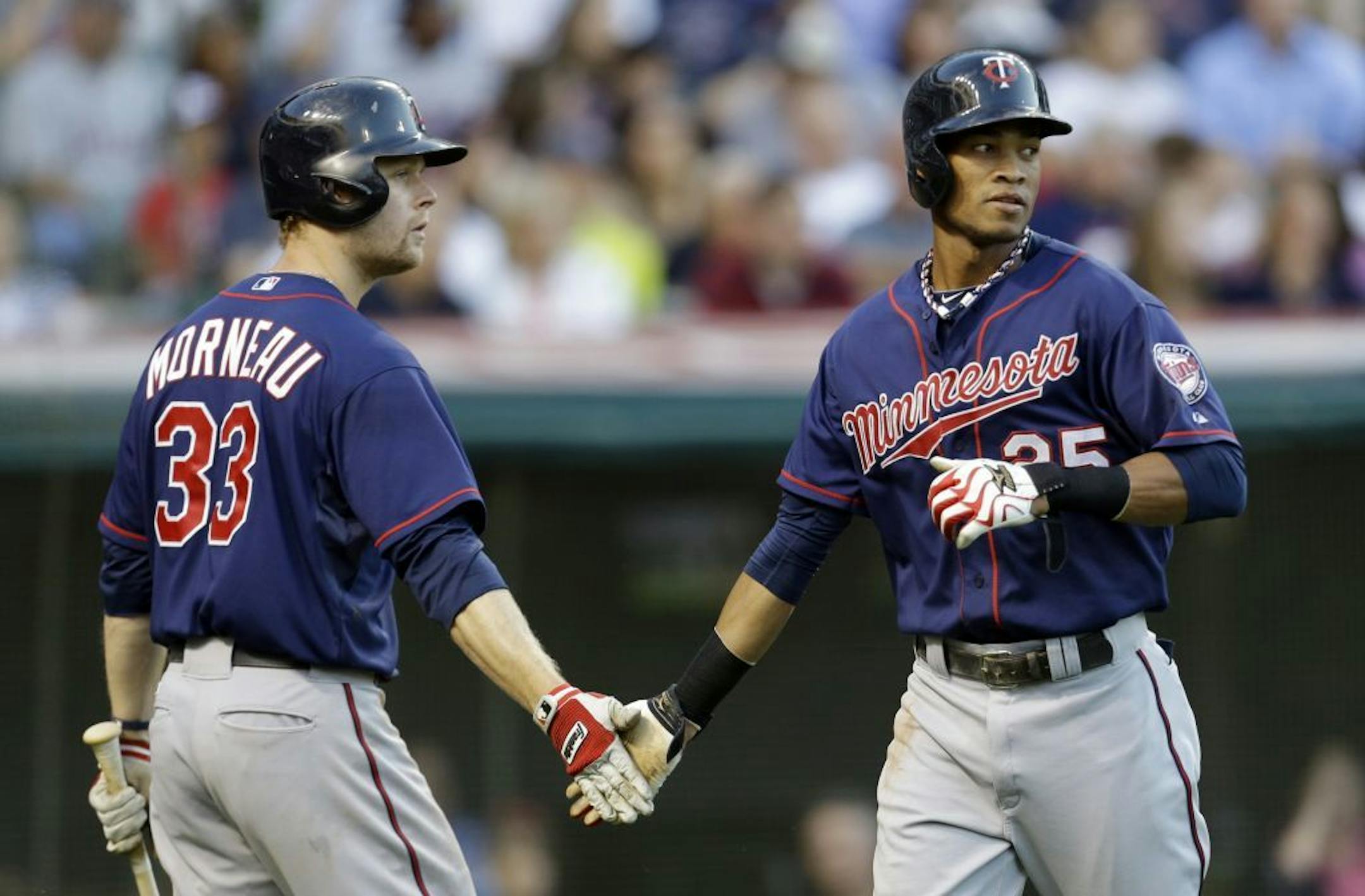 Minnesota Twins' Pedro Florimon (25) is congratulated by Justin Morneau (33) in the second inning of a baseball game against the Cleveland Indians, Friday, Aug. 23, 2013, in Cleveland. Florimon scored on an hit by Chris Herrmann.