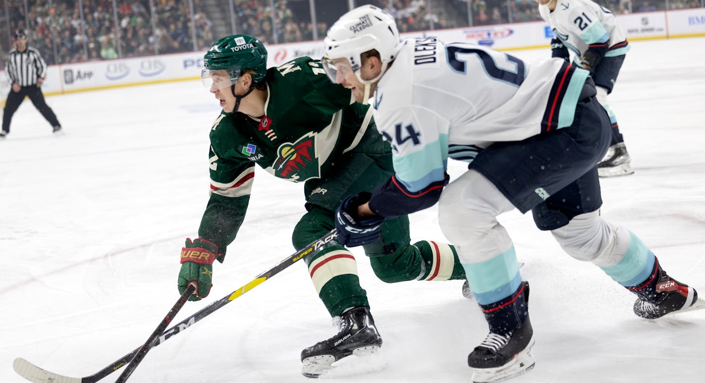 Matt Boldy (12) of the Minnesota Wild and Jamie Oleksiak (24) of the Seattle Kraken chase the puck in the first period Monday, March 27, 2023, at Xcel Energy Center in St. Paul, Minn. ] CARLOS GONZALEZ • carlos.gonzalez@startribune.com.