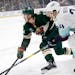 Matt Boldy (12) of the Minnesota Wild and Jamie Oleksiak (24) of the Seattle Kraken chase the puck in the first period Monday, March 27, 2023, at Xcel