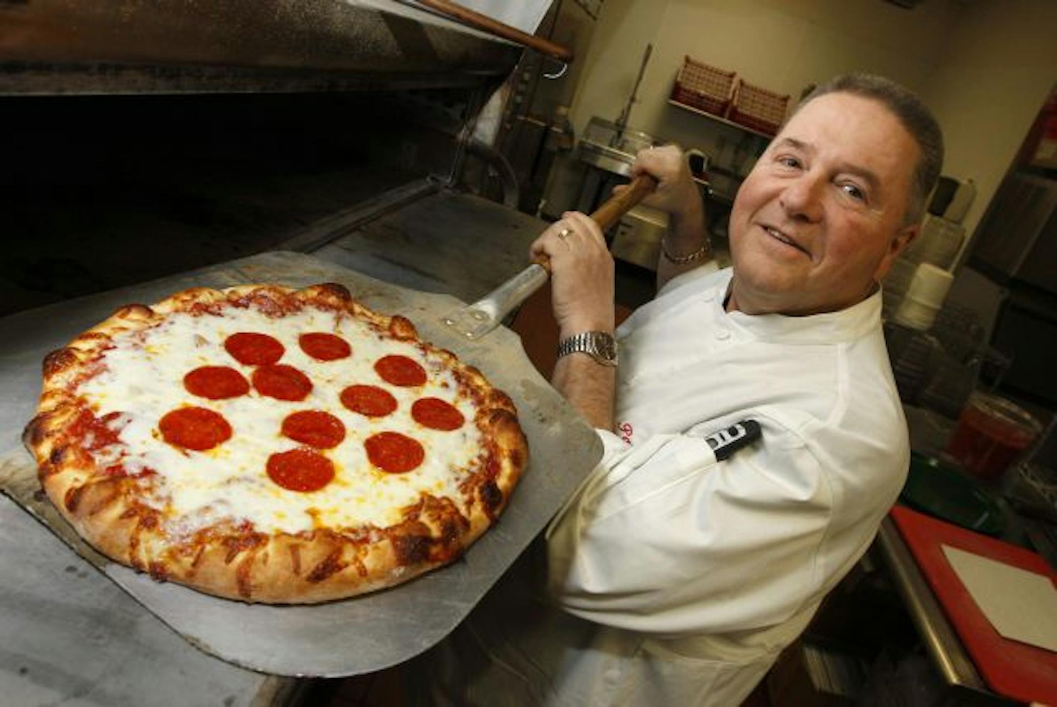 Classic hand-tossed pizza: Papa's Deli owner Mick Brogan presents a pepperoni pie at his north Minneapolis pizzeria.