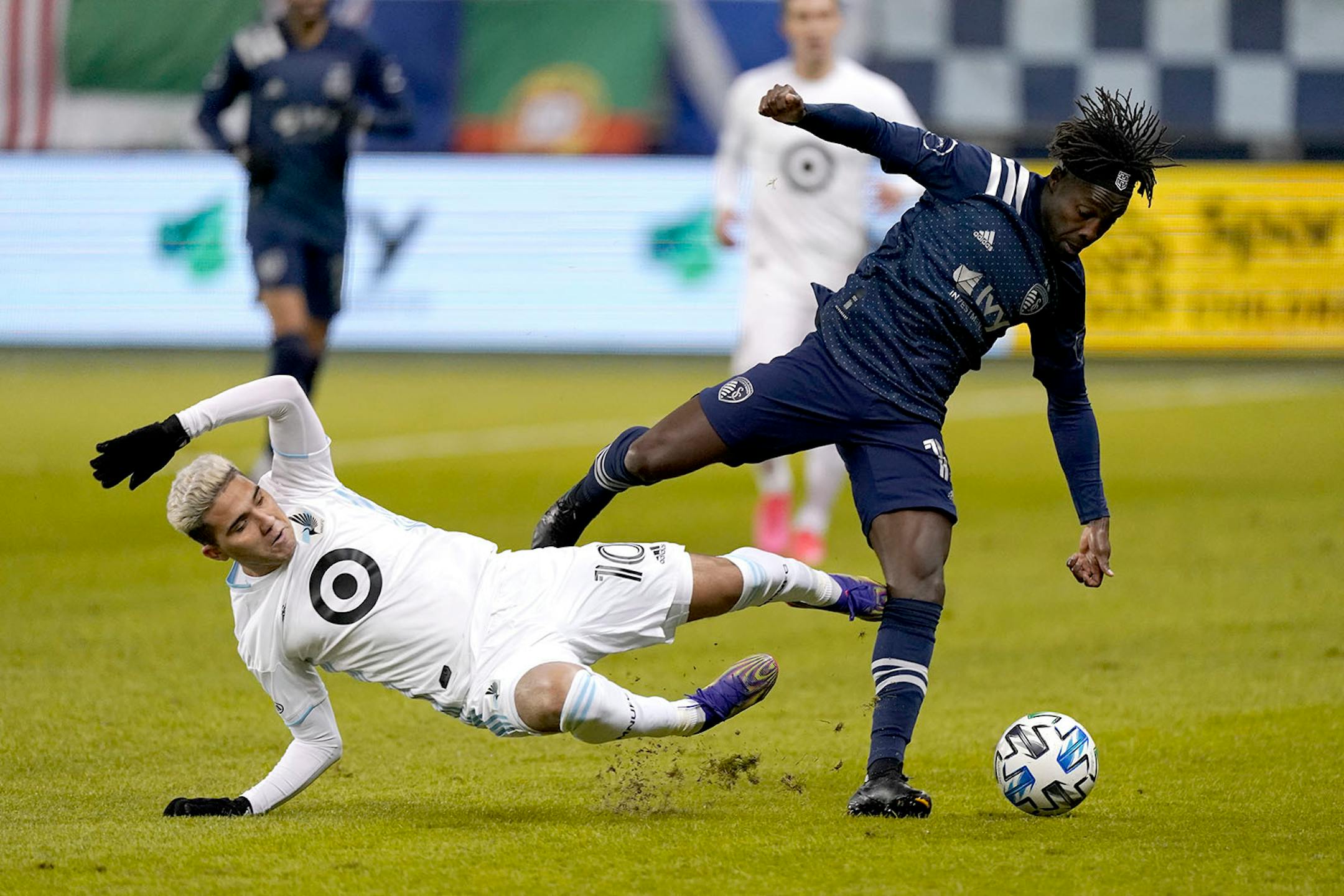 Minnesota United midfielder Emanuel Reynoso (10) and Sporting Kansas City forward Gerso (12) chase the ball during the first half of an MLS soccer match Thursday, Dec. 3, 2020, Kansas City, Kan. (AP Photo/Charlie Riedel)