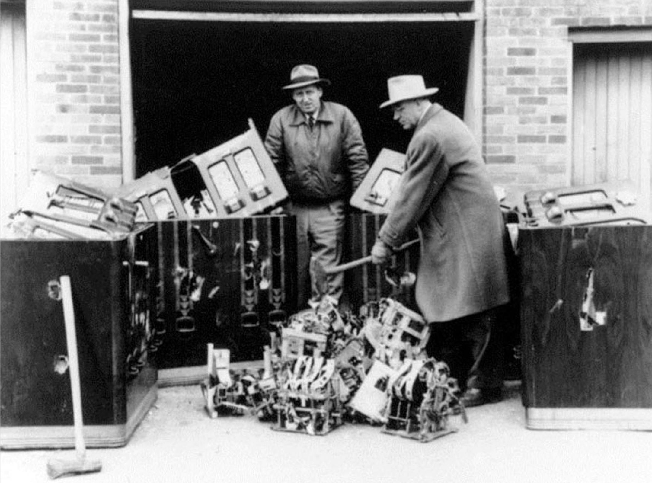 Courtesy Scott County Historical Soceity. The slot machines in the cell: An abundance of confiscated slot machines were temporarily stored in an empty Scott County jail cell. Prohibition raid: Taking an ax to destroy a moonshine production still.