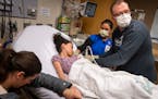 Registered nurse Joe Schwartz, from right, finds a vein to start an IV with the help of RN Shanna Jorgenson for patient Juliana Jones, 10, as her moth