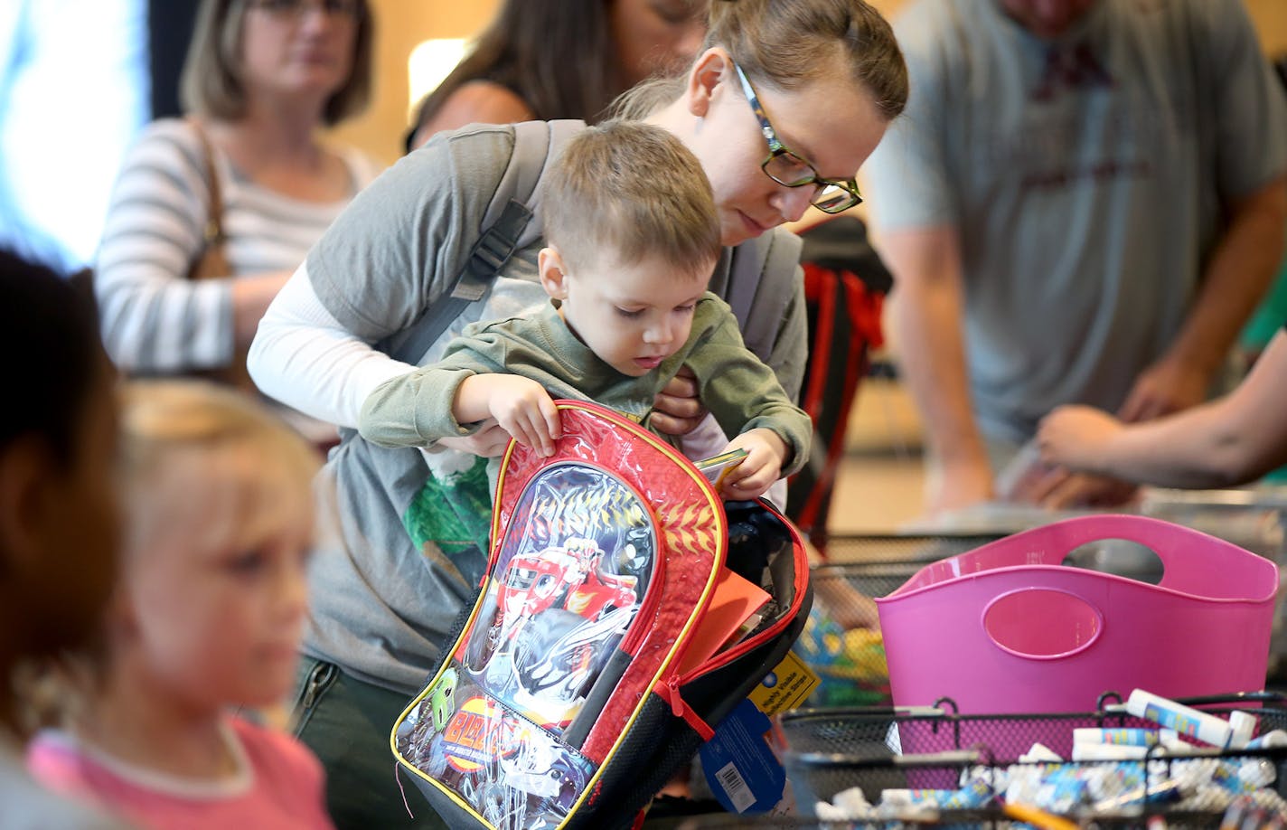 Sam Prieto lifted her son Roland Prieto, 3, to help him grab school supplies to fill a backpack at the Mall of America rotunda, Tuesday, August 18, 2015 in Bloomington, MN. They joined many families to help fill five hundred kindergarten-ready backpacks to be distributed to local students. ] (ELIZABETH FLORES/STAR TRIBUNE) ELIZABETH FLORES &#x2022; eflores@startribune.com