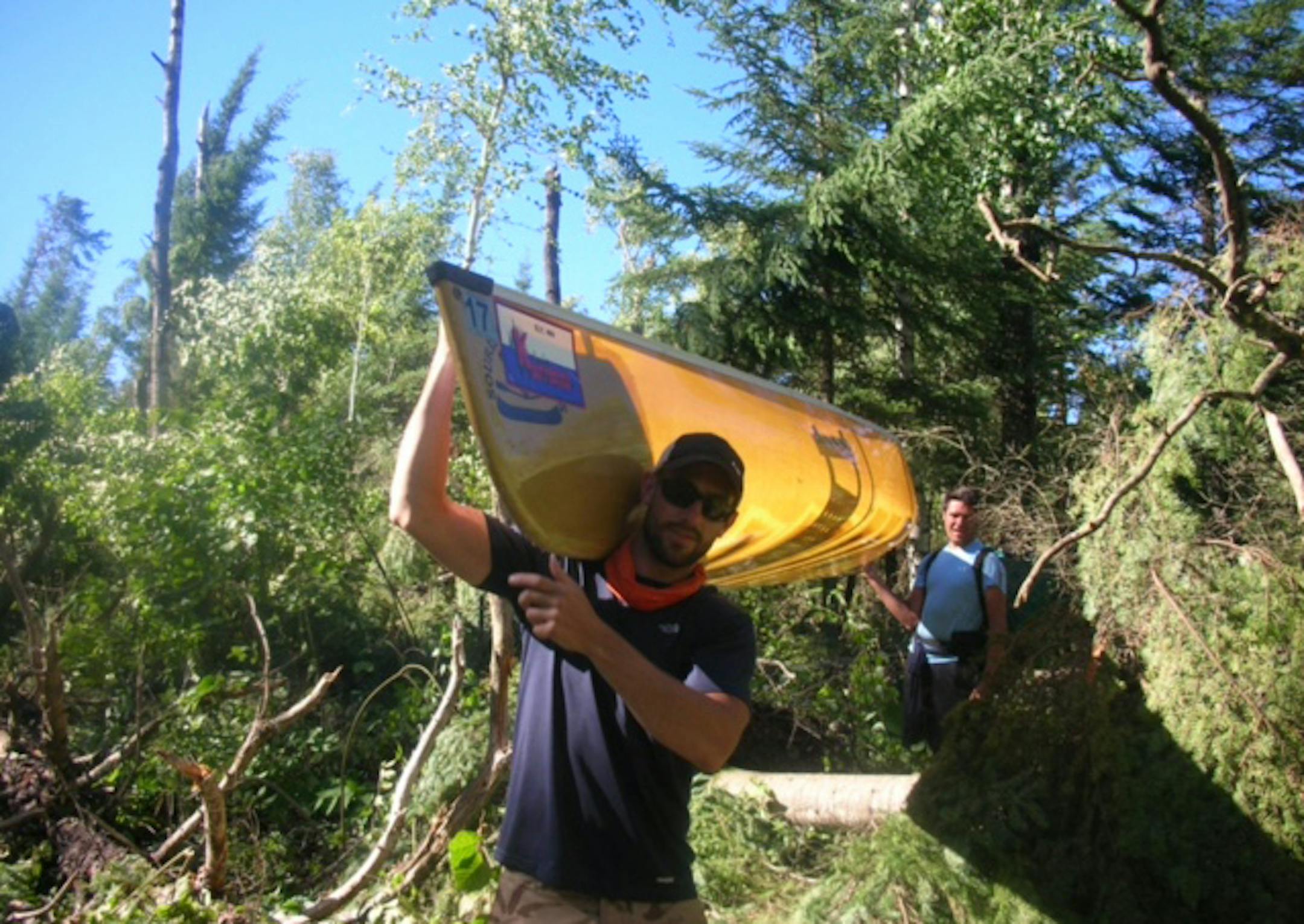 After the recent big storm swept through the boundary waters, many canoeists had to bushwack their way across portages strewn with downed trees. Here Hans Frederick, foreground, and Joe Wente tote their canoe through a maize of fallen trees.