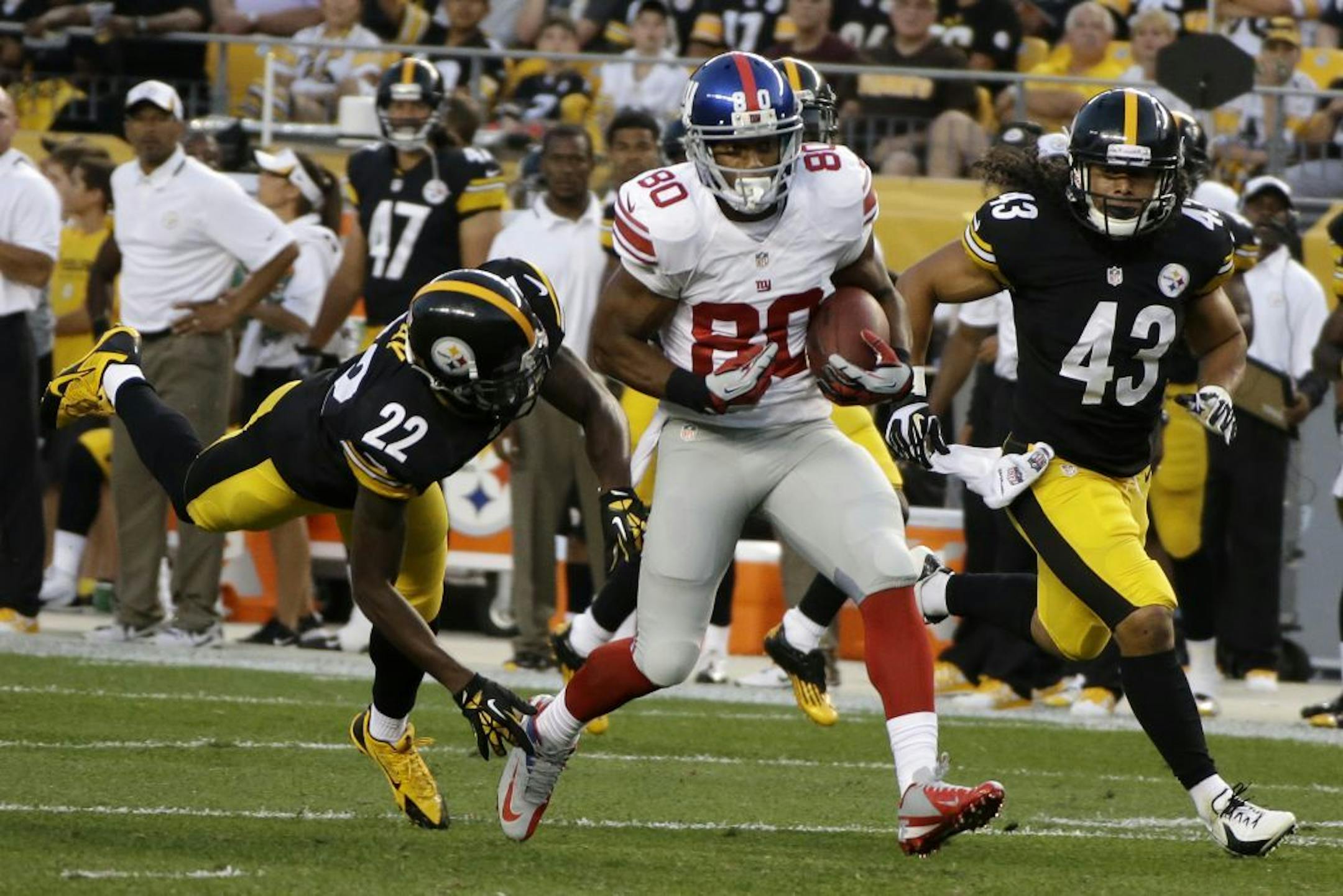 New York Giants wide receiver Victor Cruz (80) comes down with a pass from quarterback Eli Manning between Pittsburgh Steelers cornerback William Gay (22) and safety Troy Polamalu (43) for a 70-yard touchdown during the first quarter of an NFL preseason football game in Pittsburgh, Saturday, Aug. 10, 2013.