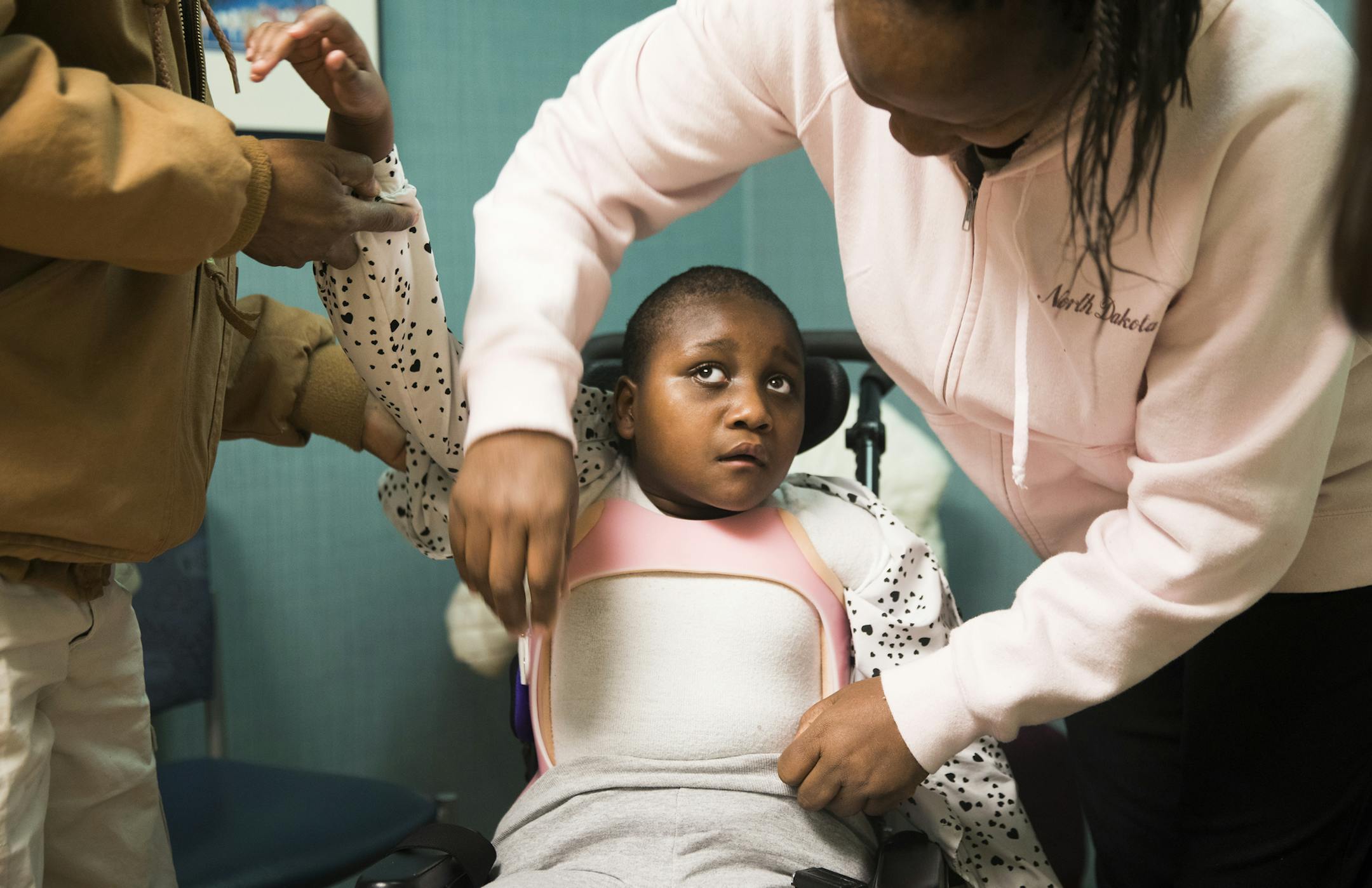 Beulah Tarus, 8, gets undressed by her parents Everlyn, right, and Samson Tarus, during a follow up visit with Janet Cortes, a certified orthotist, after receiving a TLSO brace at Gillette Children's in St. Paul. ] LEILA NAVIDI &#xef; leila.navidi@startribune.com BACKGROUND INFORMATION: The custom-design lab at Gillette Children's Hospital in St. Paul on Tuesday, February 6, 2018.