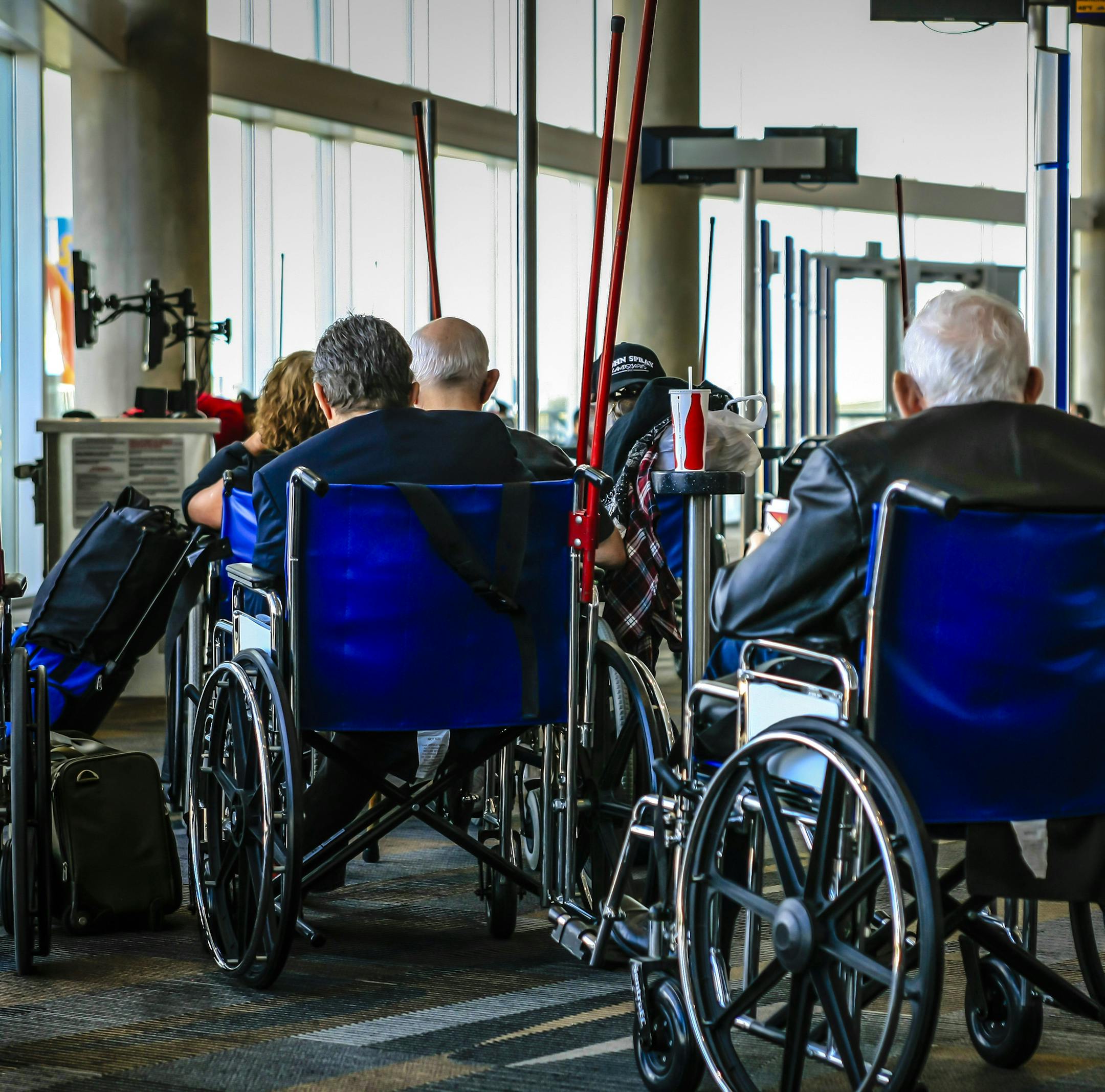 Houston, TX, USA - December 5, 2012: Handicapped travelers in wheelchairs wait in line to a the gate to board their plane at Houston Int. airport in Texas