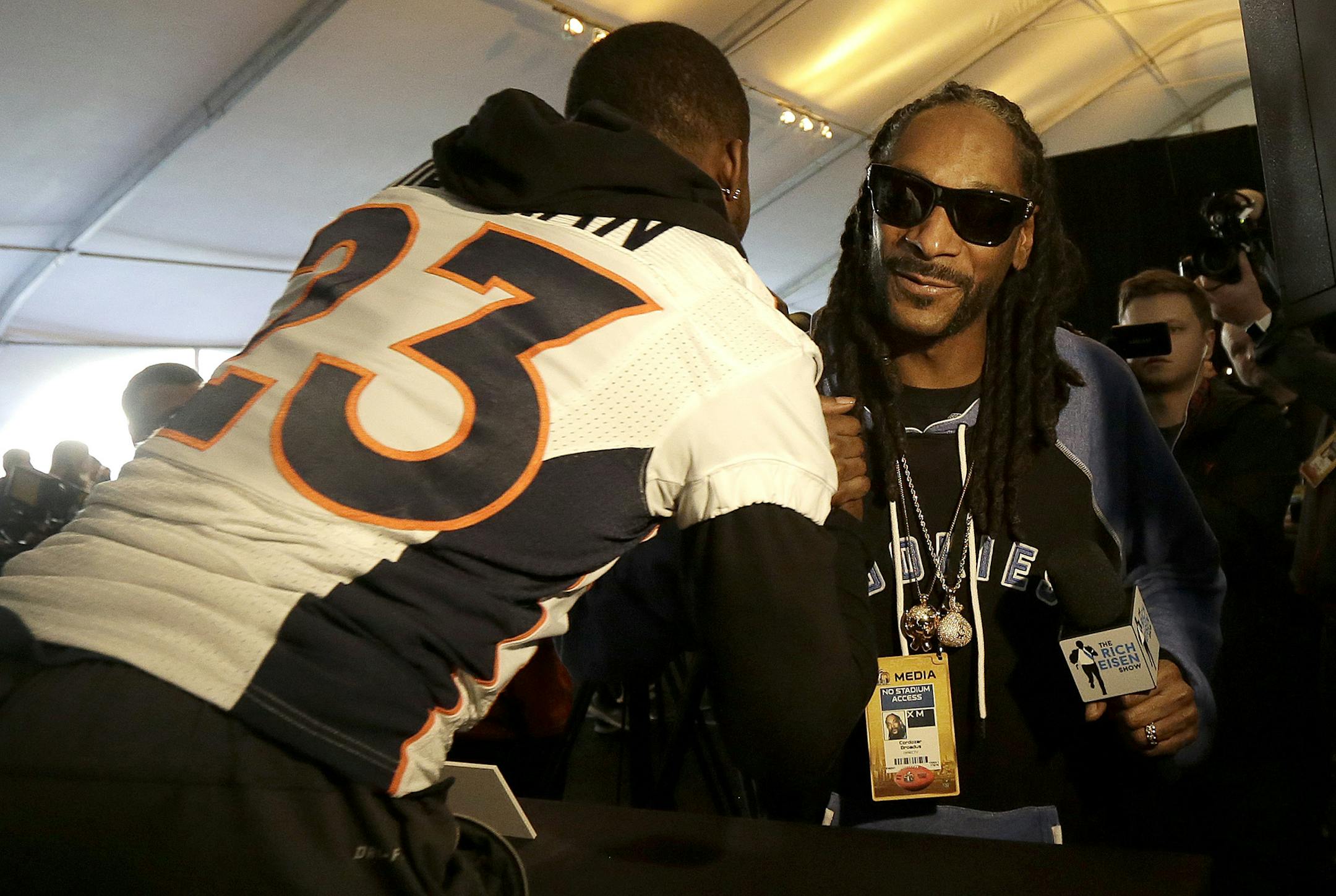 Denver Broncos running back Ronnie Hillman (23) is greeted by musician Snoop Dogg while speaking to reporters in Santa Clara, Calif., Thursday, Feb. 4, 2016. (AP Photo/Jeff Chiu)