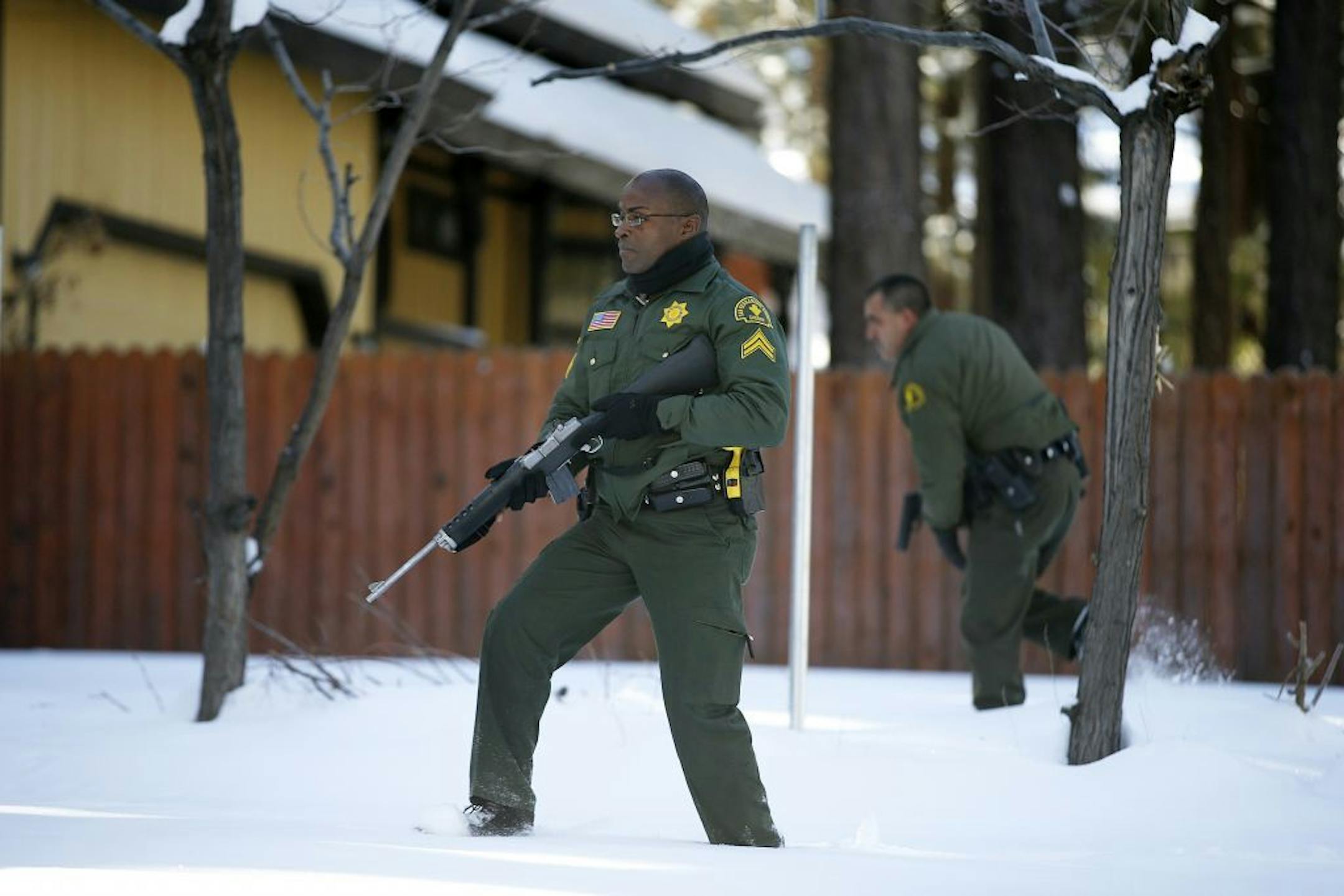 San Bernardino County Sheriff's officers Ken Owens, center, and Bernabe Ortiz search a home for former Los Angeles police officer Christopher Dorner in Big Bear Lake, Calif, Sunday, Feb. 10, 2013. The hunt for the former Los Angeles police officer suspected in three killings entered a fourth day in snow-covered mountains Sunday, a day after the police chief ordered a review of the disciplinary case that led to the fugitive's firing and new details emerged of the evidence he left behind.