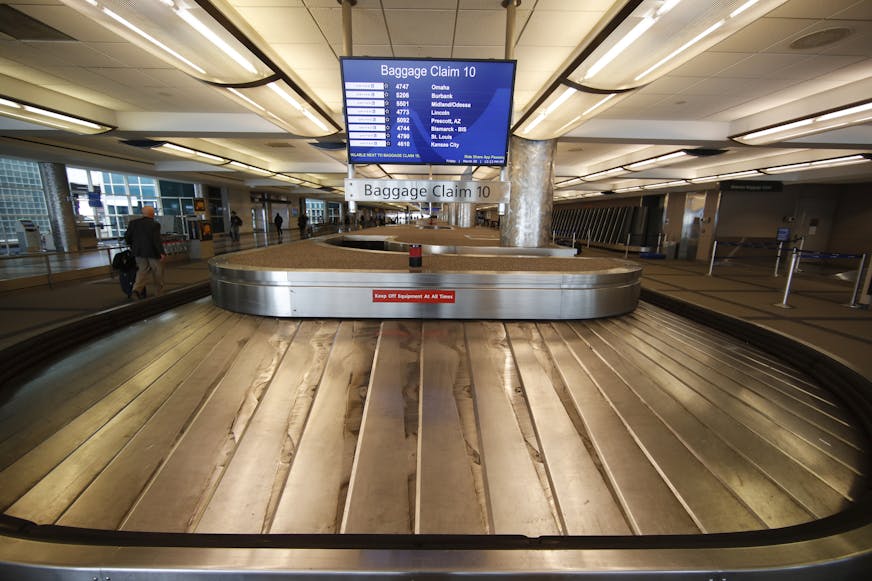 FILE - In this March 20, 2020 file photo, an empty baggage carousel spins in Denver International Airport as travelers deal with the spread of the coronavirus in Denver. Airline service in the United States is teetering on the brink of collapse, with near-empty planes and coronavirus-caused outbreaks that have left some air traffic control towers empty. Even with sharply reduced schedules, airlines are consolidating some of the remaining flights because passengers aren&#x2019;t showing up. (AP P