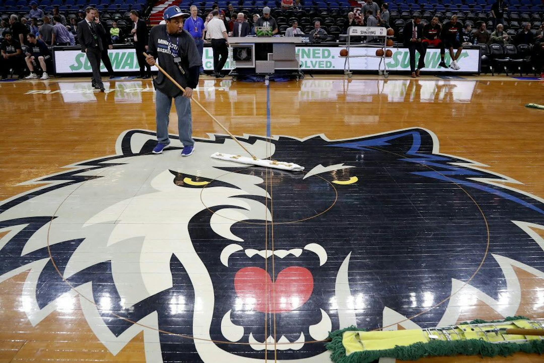 Crews wiped the Target Center floor on Monday night. Ice under the floor and unseasonably warm and humid weather caused condensation on the wood floor.