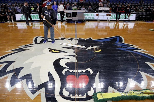 Crews wiped the Target Center floor on Monday night. Ice under the floor and unseasonably warm and humid weather caused condensation on the wood floor