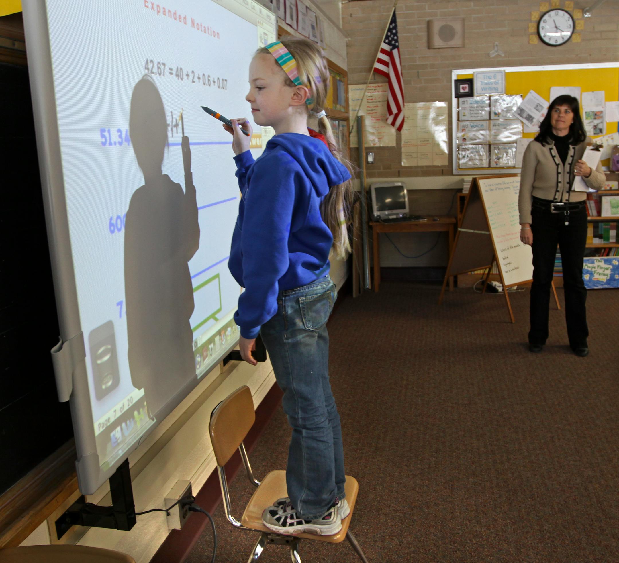 (left to right) Lily Den Hartog (cq) used an electronic ActivBoard to answer math review questions as 3rd grade math teacher Mary Jo Merickel watched at Glen Lake Elementary School. The ActivBoard is like a huge computer screen were students can use remote controls to answer questions from their desks or use pens to work problems on the board.