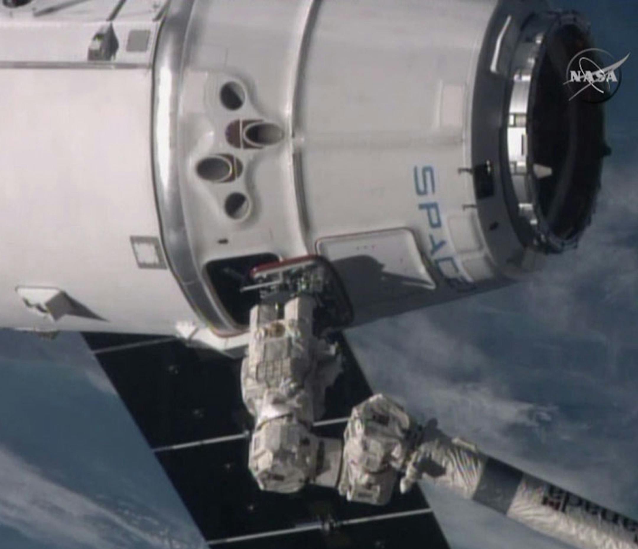 In this video frame grab provided by NASA, the the International Space Station's robotic arm, lower right, operated by station commander Butch Wilmore, reaches for the SpaceX Dragon spacecraft as the soar more than 260 miles above the Mediterranean Sea on Monday, Jan. 12, 2015. The capsule delivered 5,000 pounds of precious cargo, including much-needed groceries and belated Christmas presents, to the space station's six astronauts. (AP Photo/NASA TV)
