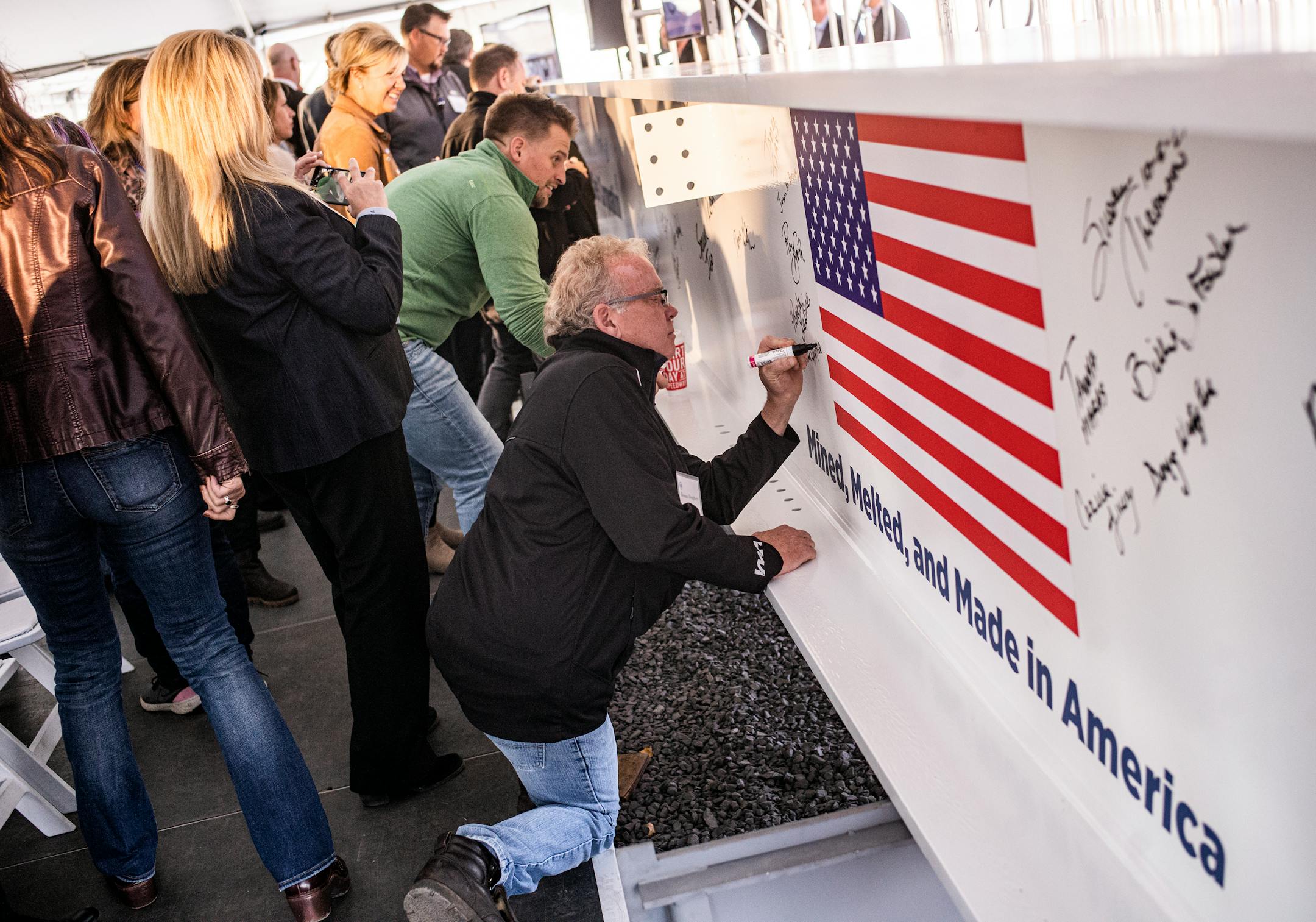 Guests sign a support beam that will go into US Steel's $150 million DR grade pellet plant in Keewatin.