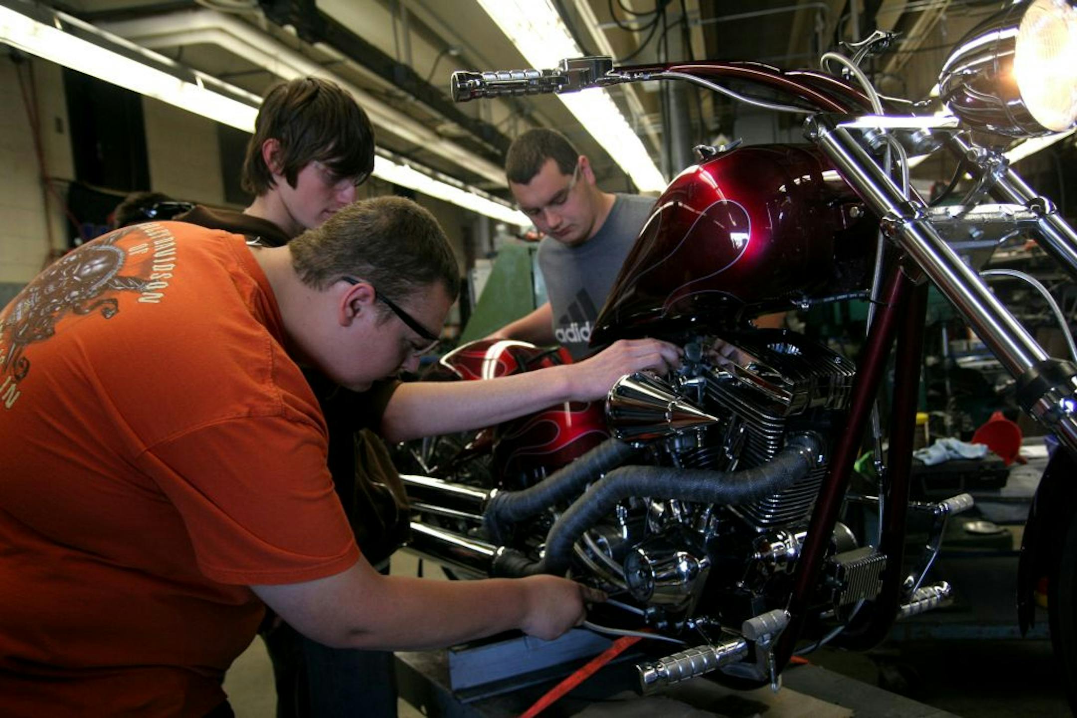 PHOTO BY MARIA BACA. John Koller, Jesse Hagford and Mitchell Carlson worked to find the source of an oil leak on the custom chopper that was their machining class project over the past four years. Koller and Hagford graduated in March, but have been coming back to the chopper class to see the project through. Carlson is a junior.