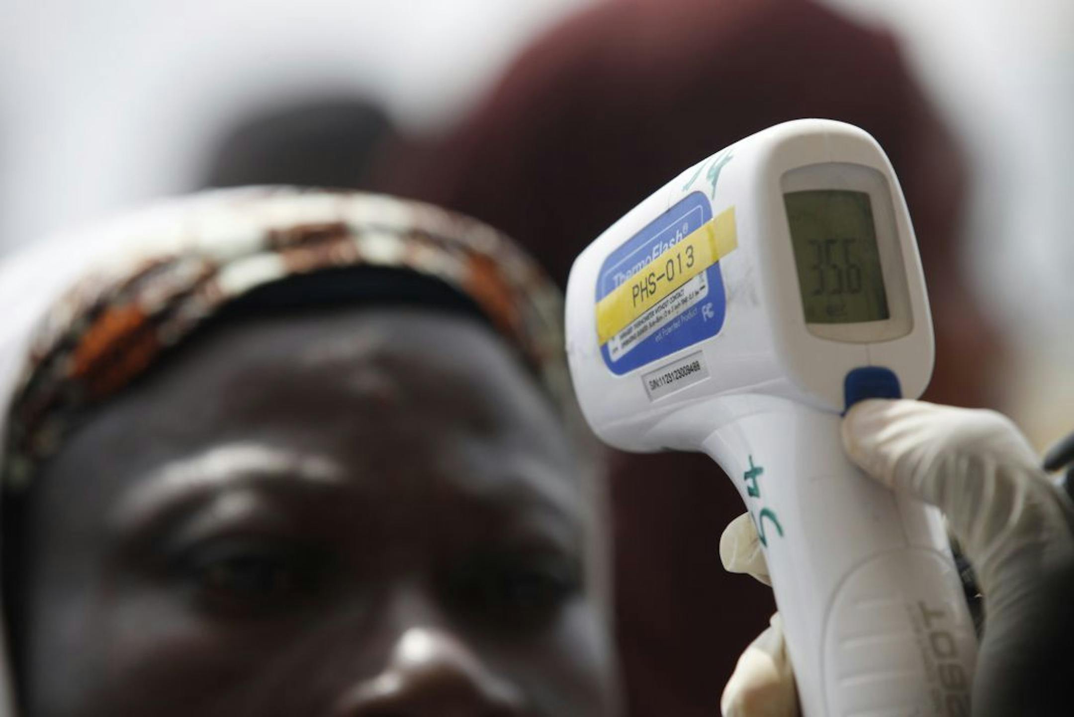 A Nigerian port official uses a thermometer to screen Muslim pilgrims for Ebola at the Hajj camp before boarding a plane for Saudi Arabia at the Murtala Muhammed International Airport in Lagos, Nigeria Thursday, Sept, 18. 2014.