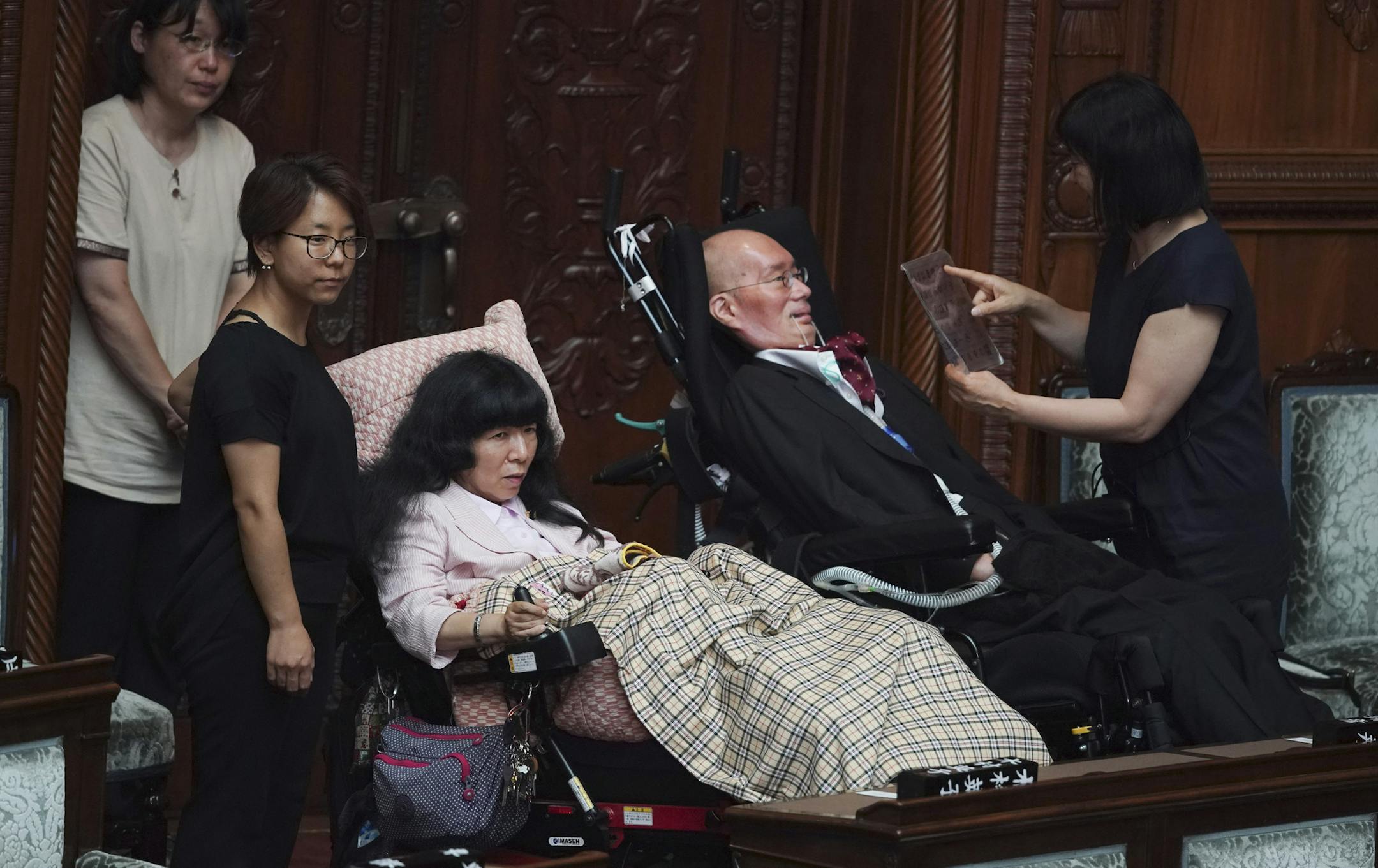 Newly-elected lawmakers in wheelchairs, Eiko Kimura, center left, and Yasuhiko Funago, of the opposition party Reiwa Shinsengumi, attend the opening of an extraordinary Diet session at the upper house of parliament Thursday, Aug. 1, 2019. Funago has amyotrophic lateral sclerosis and Eiko Kimura has cerebral palsy. They represent an opposition group led by actor-turned-politician Taro Yamamoto.(AP Photo/Eugene Hoshiko) ORG XMIT: XEH109