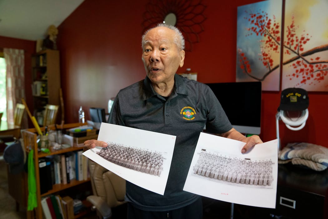 Seiki Oshiro holds photos of two graduating classes of the Military Intelligence Service Language School from the 1940s.