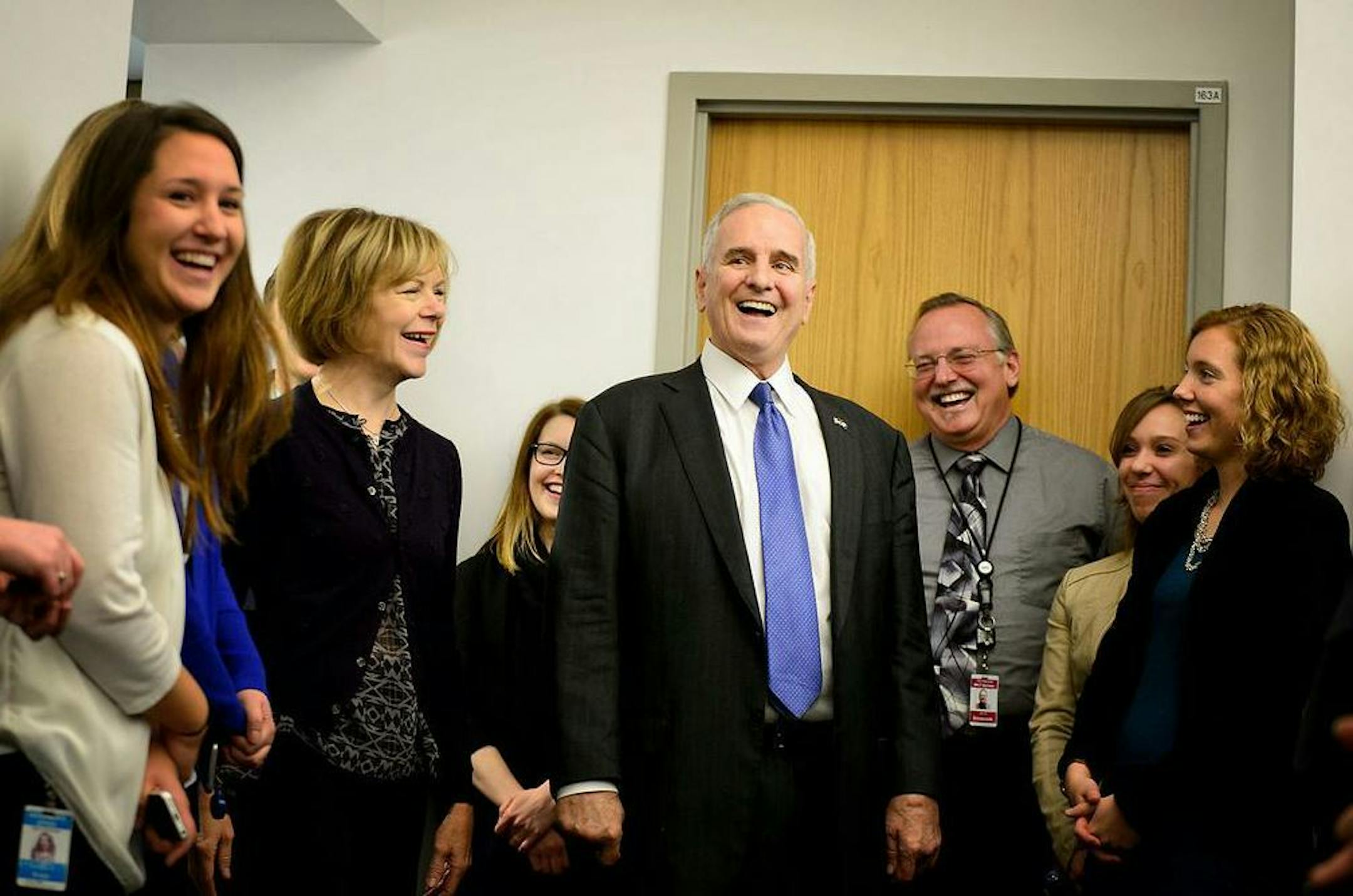 Gov. Mark Dayton, center, and his running mate Tina Smith, second from left, enjoyed a light moment with staffers when they arrived at work Wednesday.