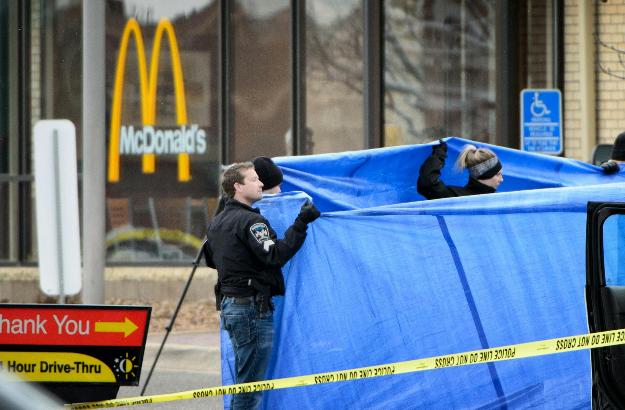 Burnsville Police held a tarp around the body as BCA investigators and Medical Examiners investigated a shooting that occured in a McDonald's parking lot Thursday morning involving a Burnsville police officer. ] GLEN STUBBE * gstubbe@startribune.com Thursday March 17, 2016 EDS, graphic content, covered body of victim in parking lot