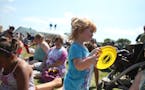 Skylar Hagerstrom, 2, of Norwood Young America, played the yellow disc like a tambourine as she and other listened to music at Taste of Minnesota in W