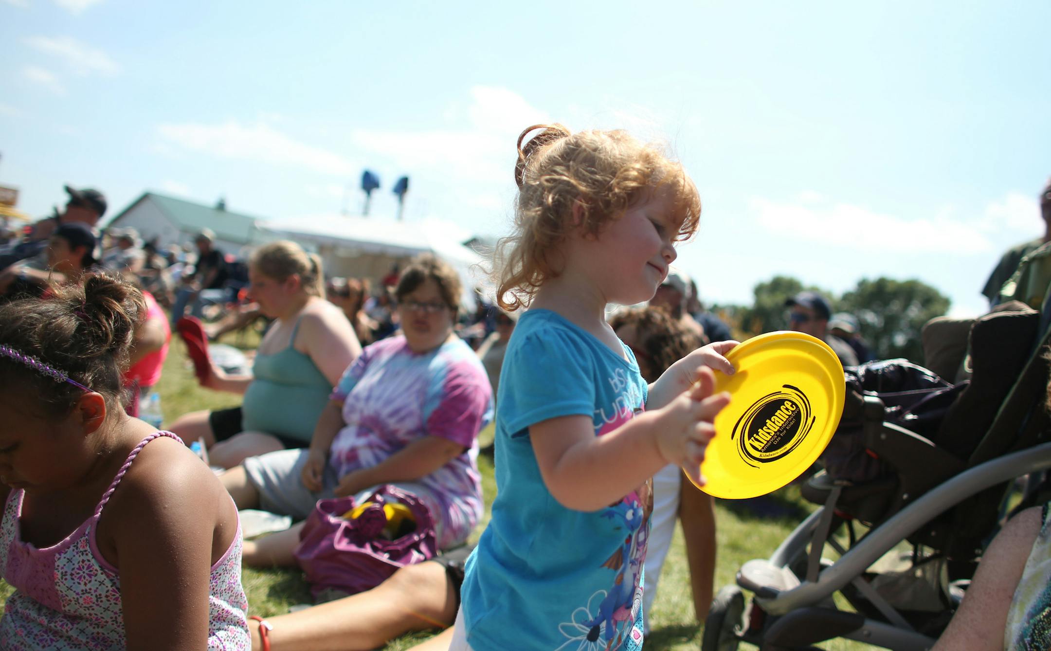 Skylar Hagerstrom, 2, of Norwood Young America, played the yellow disc like a tambourine as she and other listened to music at Taste of Minnesota in Waconia in 2014.