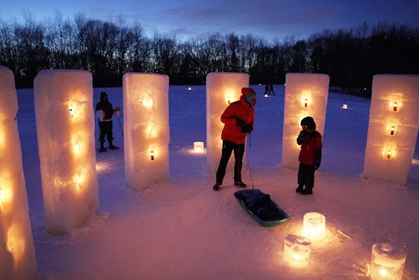 Gregg Lind checked on his son Galen Beil, 8, as they and Melissa Arbuckle, left, looked over the Ice Henge sculpture during the Luminary Loppet Friday
