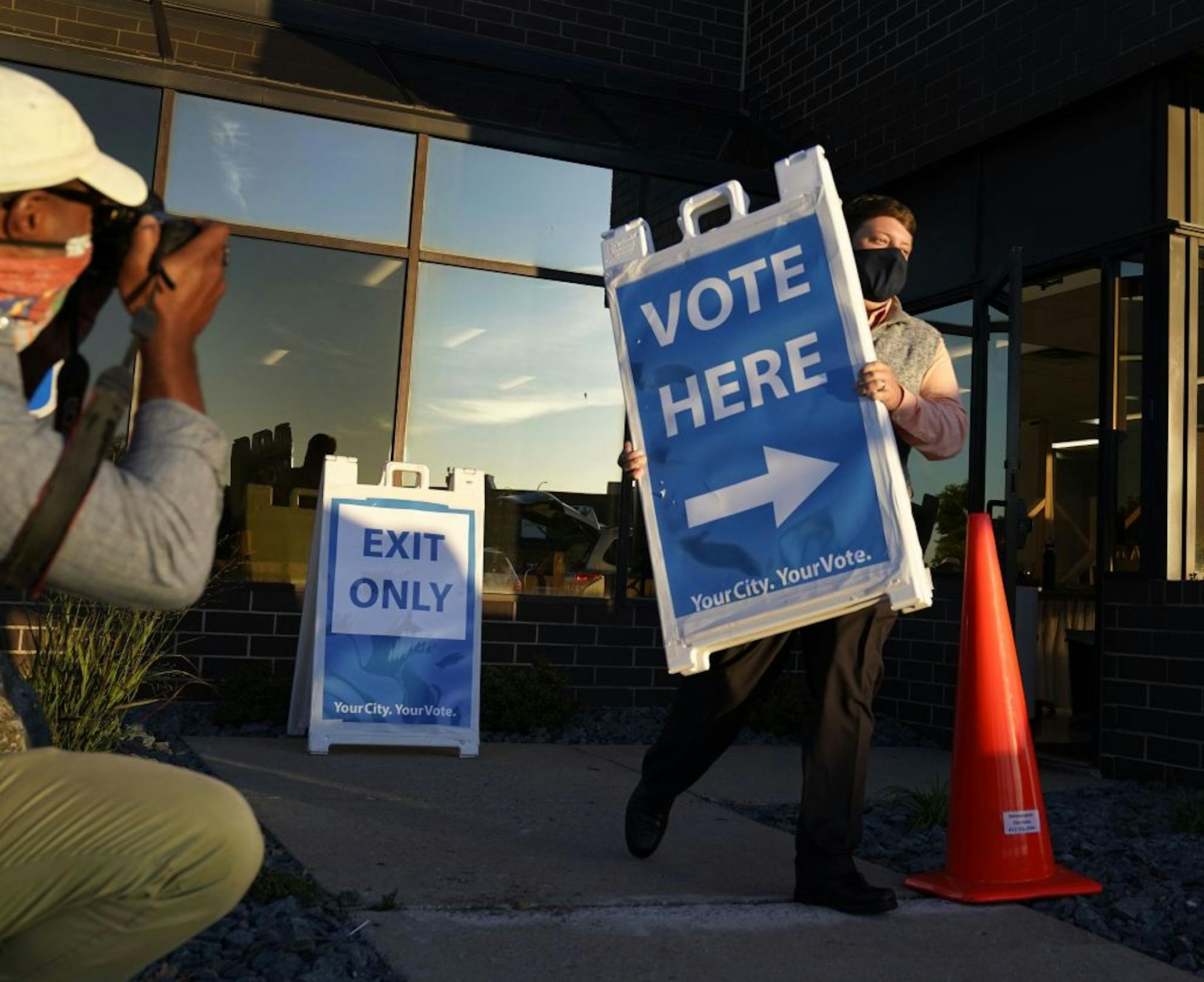 Election worker Nick Stumo-Langer carried a voting sign to a waiting vehicle to place near the Minneapolis Elections and Voter Services for early voting Friday in Minneapolis.