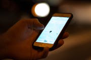 An Uber customer checked the status of his ride on his phone while waiting at the intersection of Lagoon Avenue and Hennepin Avenue late Saturday nigh