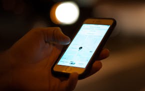 An Uber customer checked the status of his ride on his phone while waiting at the intersection of Lagoon Avenue and Hennepin Avenue late Saturday nigh