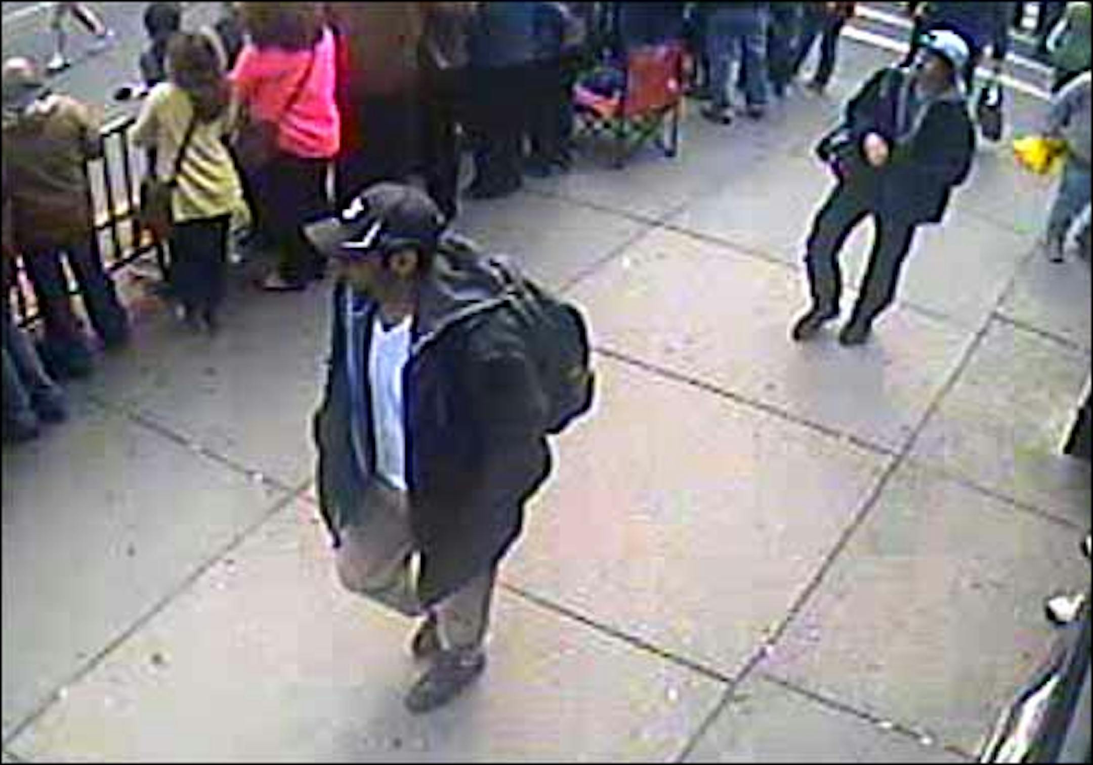 This image taken from video shows what the FBI are calling suspect number 1, front, in black cap, and suspect number 2, in white cap, back right, walking near each other through the crowd in Boston on April 15, 2013, before the explosions.