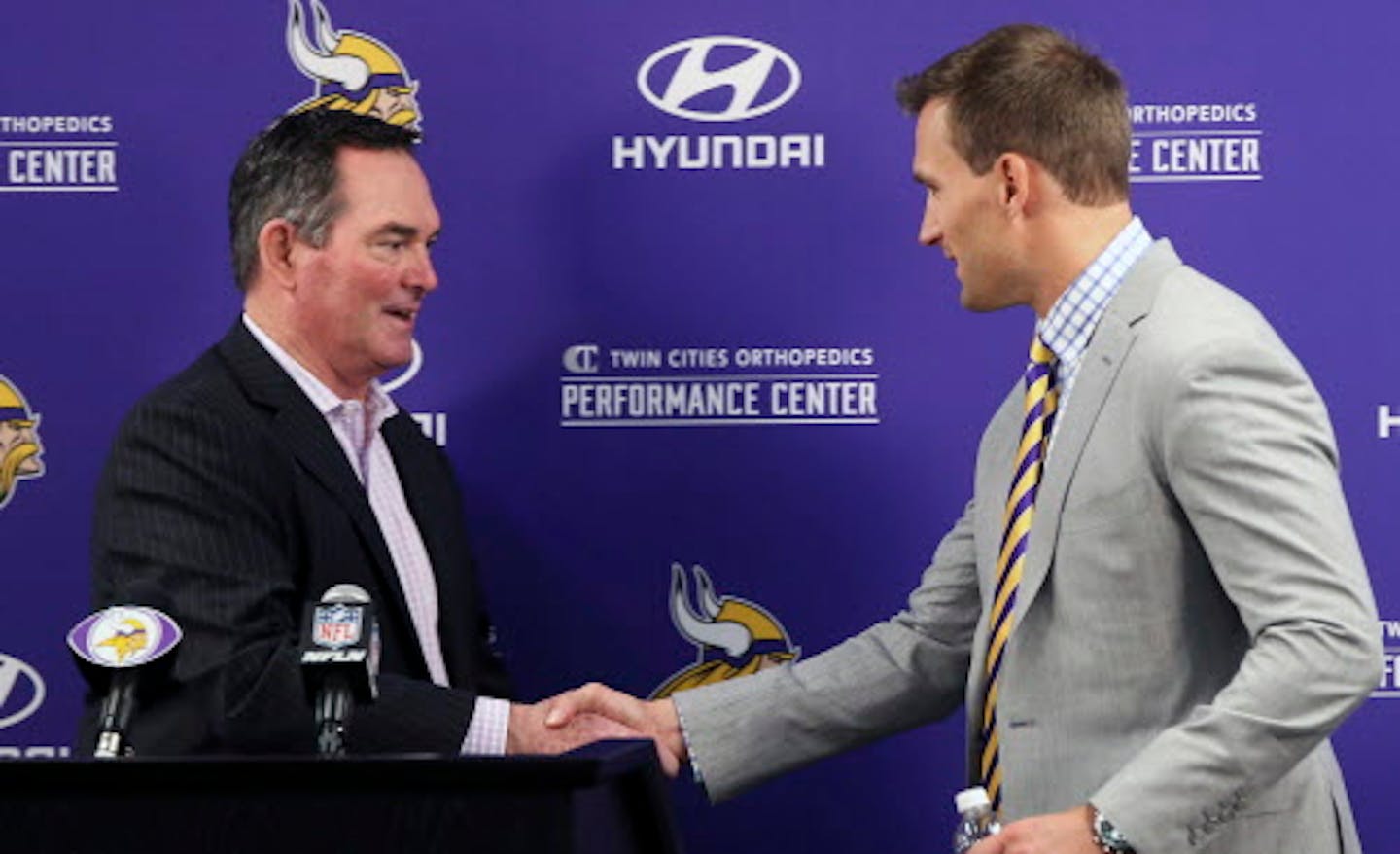 Minnesota Vikings new quarterback Kirk Cousins, right, is welcomed to the podium by head coach Mike Zimmer before addressing the media at a news conference after he was introduced after signing a three-year, $84 million contract at the NFL football team's new headquarters Thursday, March 15, 2018, in Eagan, Minn. (AP Photo/Jim Mone)