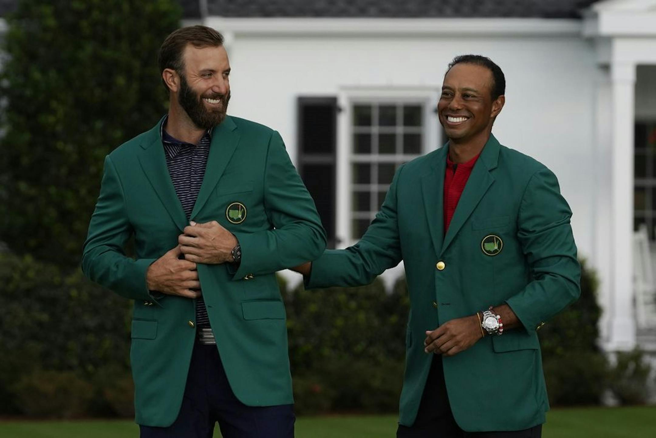 Tiger Woods stands next to Masters champion Dustin Johnson with his green jacket after his victory at the Masters golf tournament Sunday, Nov. 15, 2020, in Augusta, Ga.