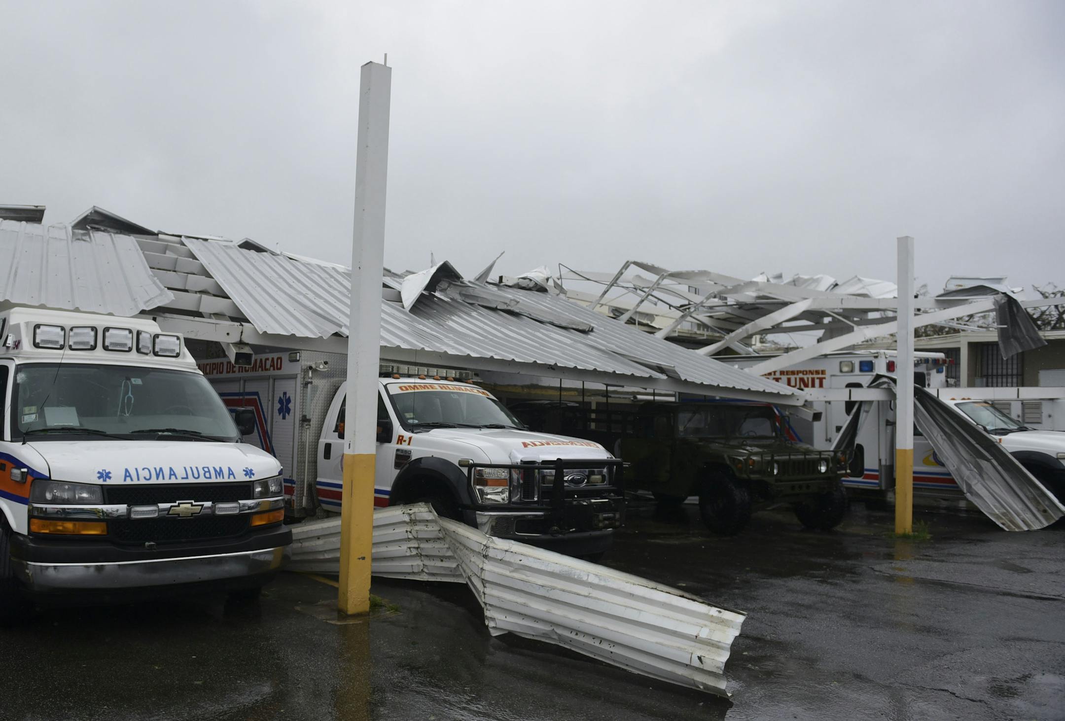 Rescue vehicles from the Emergency Management Agency stand trapped under an awning during the impact of Maria, a Category 5 hurricane that hit the eastern region of the island, in Humacao, Puerto Rico, Wednesday, Sept. 20, 2017. The U.S. National Hurricane Center says Maria has lost its major hurricane status, after raking Puerto Rico. But forecasters say some strengthening is in the forecast and Maria could again become a major hurricane by Thursday. (AP Photo/Carlos Giusti)