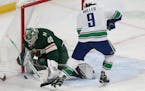 Vancouver Canucks' J.T. Miller tries to score a goal as Minnesota Wild's goalie Devan Dubnyk blocks the net in the first period of an NHL hockey game 