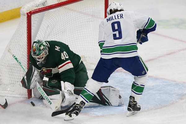 Vancouver Canucks' J.T. Miller tries to score a goal as Minnesota Wild's goalie Devan Dubnyk blocks the net in the first period of an NHL hockey game 