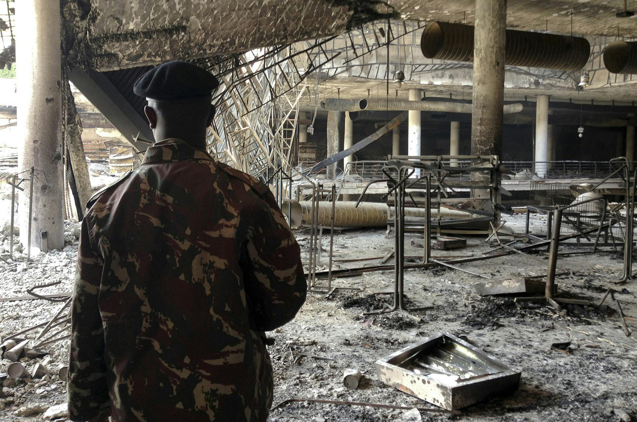 A Kenyan policeman walks through the remains of the Nakumatt supermarket in the Westgate Mall in Nairobi, Kenya Tuesday, Oct. 1, 2013. Kenyan President Uhuru Kenyatta says Kenya will keep its troops in Somalia to help that country's beleaguered government battle the armed Islamic extremist group al-Shabab, which attacked the mall in Nairobi on Sept. 21 claiming at least 67 lives. (AP Photo/Jason Straziuso) ORG XMIT: MIN2013100716554456