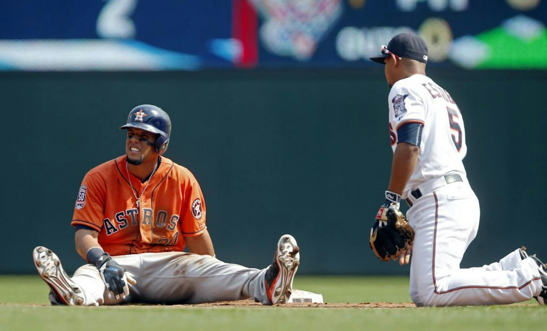 Carlos Gomez, left, remains seated momentarily after he was tagged out on a pickoff by Minnesota Twins shortstop Eduardo Escobar, right, in the second inning of a baseball game, Sunday, Aug. 30, 2015, in Minneapolis.