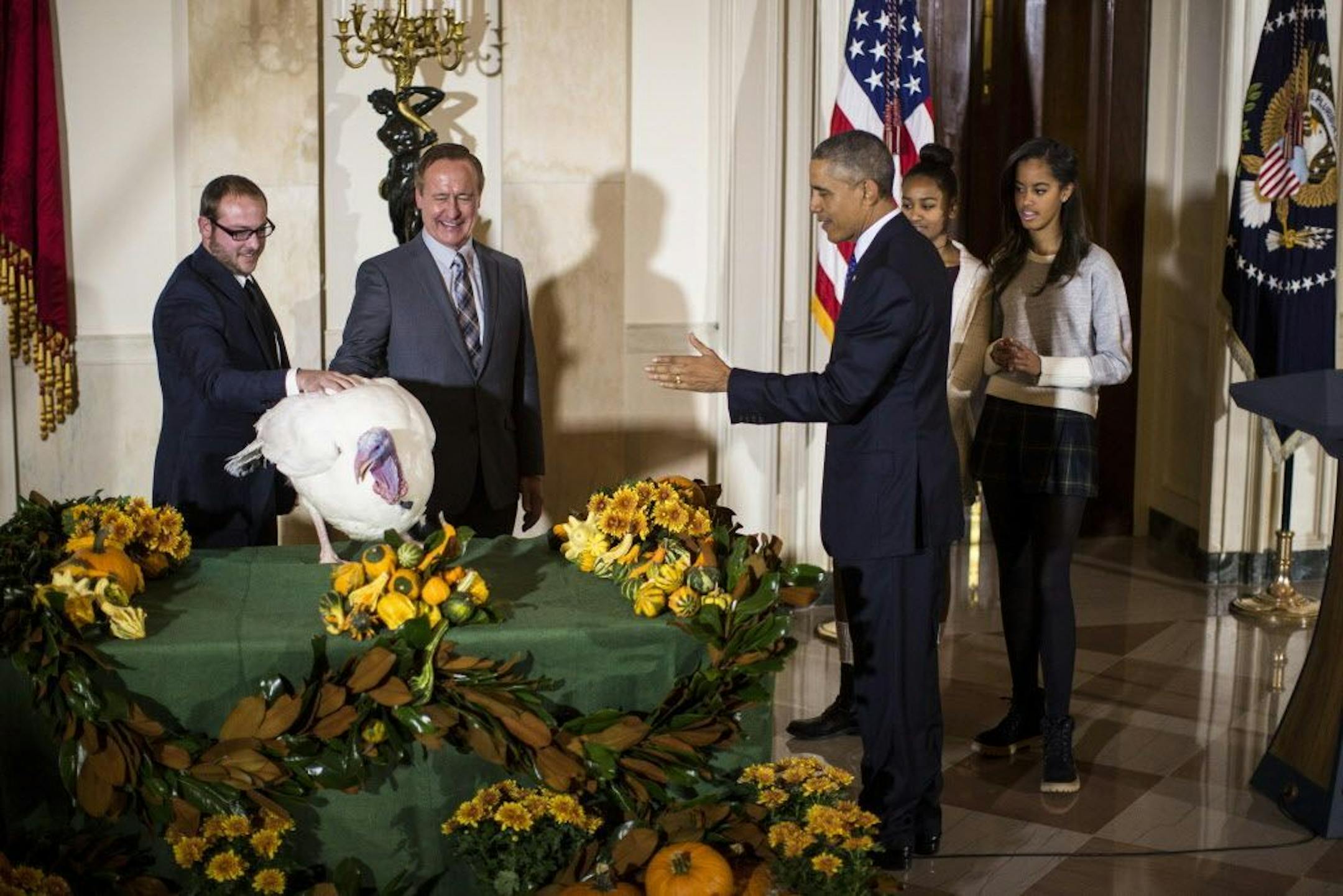 President Barack Obama pardons Cheese, the National Thanksgiving Turkey, as his daughters, Sasha and Malia, right, look on during the 67th anniversary of the National Thanksgiving Turkey presentation in the Grand Fourier at the White House in Washington, Nov. 26, 2014.