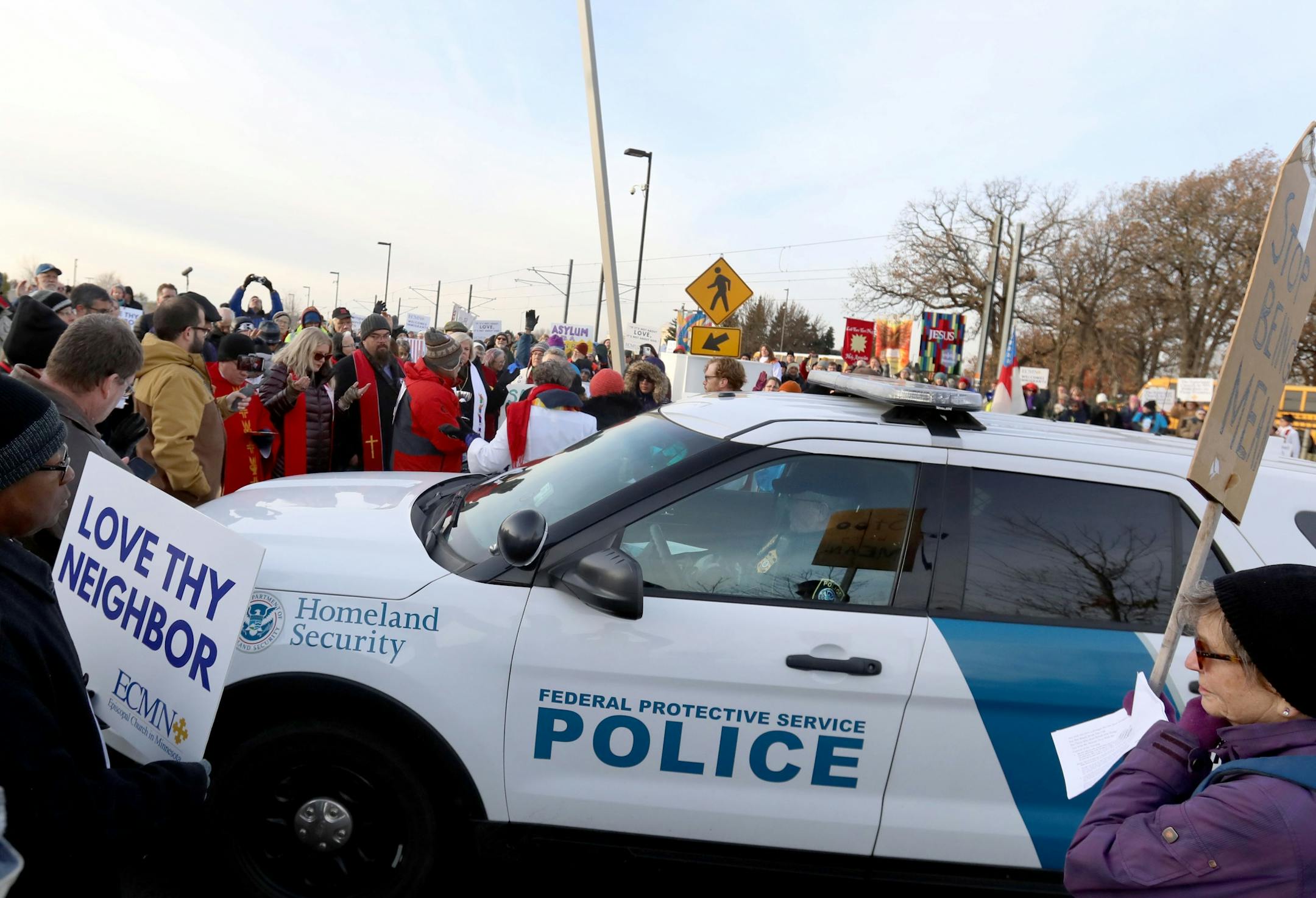 A Homeland Security police officer uses his vehicle to block the path of clergy members attempting to get inside the Whipple Federal Building to offer prayer and communion for detainees and their guards Tuesday, Oct. 29, 2019, in St. Paul, MN. Clergy and protestors gathered for a service and communion outside the Whipple Federal Building and to protest the naming of the building after the Episcopal bishop because deportations and other actions at the courthouse are in opposition to the beliefs o