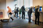 Voters filled out ballots during in-person absentee envelope voting Thursday, Oct. 27, 2022 at the Ramsey County Library in Roseville, Minn. ]
