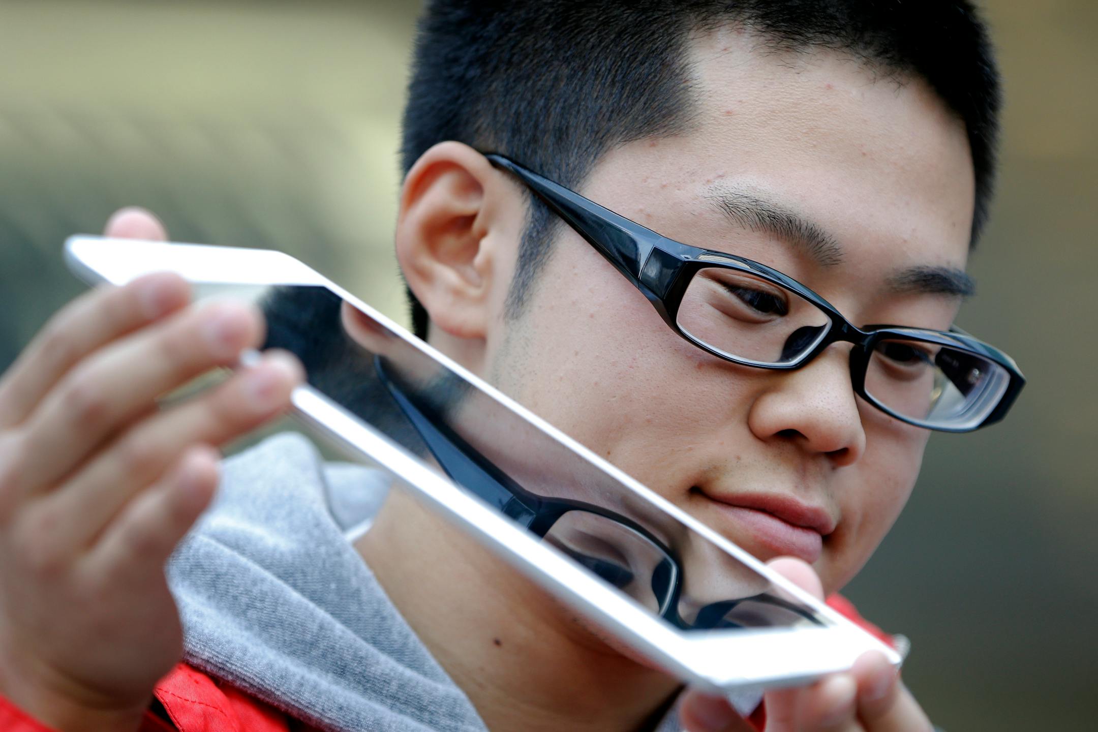 A customer displays a newly purchased Apple Inc. iPad Air to the media outside the company's store in the Ginza district of Tokyo, Japan, on Friday, Nov. 1, 2013. Apple Inc.'s forecast for the slowest holiday sales growth in a half decade reflects how iPhones and iPads aren�t providing the growth surges they once did as competition accelerates in the saturated mobile market. Photographer: Kiyoshi Ota/Bloomberg