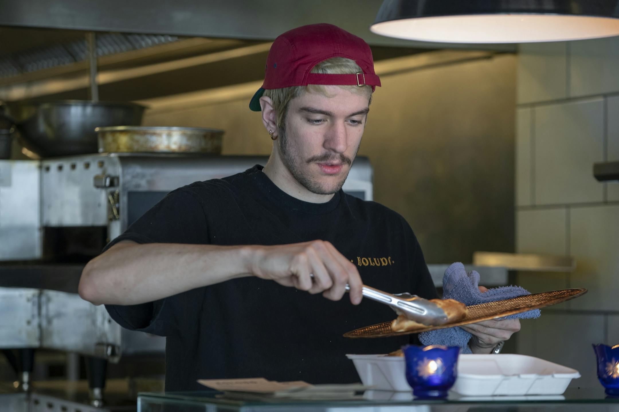 One of Boludo's cooks, Michael Belsito tended to customers at the counter filling an order of empanadas, Thursday, March 7, 2019 in Minneapolis, MN.