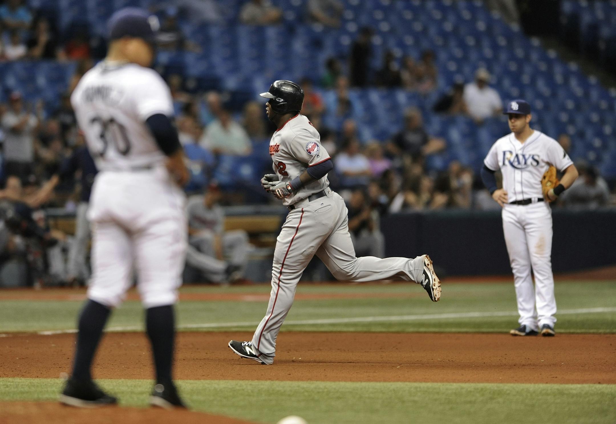 Tampa Bay Rays reliever Erasmo Ramirez, left, and third baseman Evan Longoria, right, look on as Minnesota Twins' Miguel Sano circles the bases after hitting a solo home run during the eighth inning of a baseball game Friday, Aug. 5, 2016, in St. Petersburg, Fla.