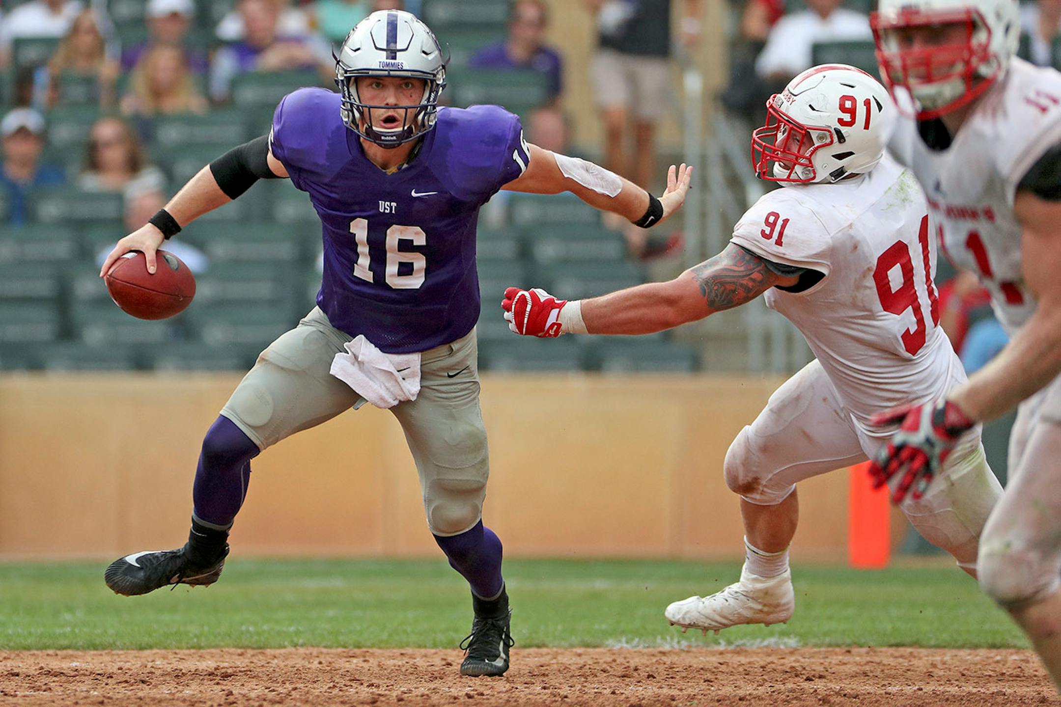 University of St. Thomas quarterback Jacques Perra (16) tried to fiend off St. John's University defensive lineman Mat Hobby (91) as he ran the ball in the second half.