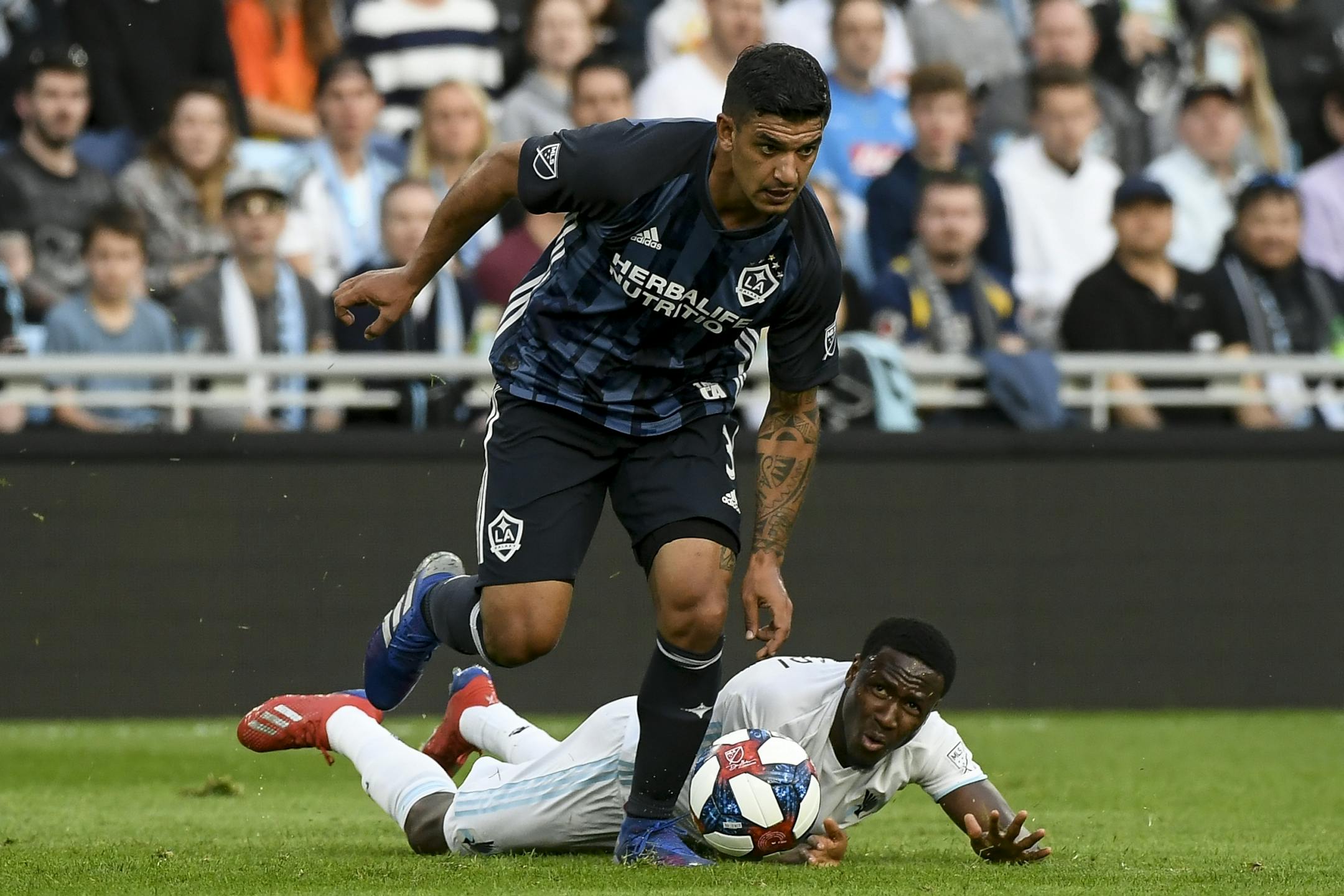 Minnesota United forward Abu Danladi (99) fell to the turf as he was defended by Los Angeles Galaxy midfielder Jonathan dos Santos (8) in the first half.
